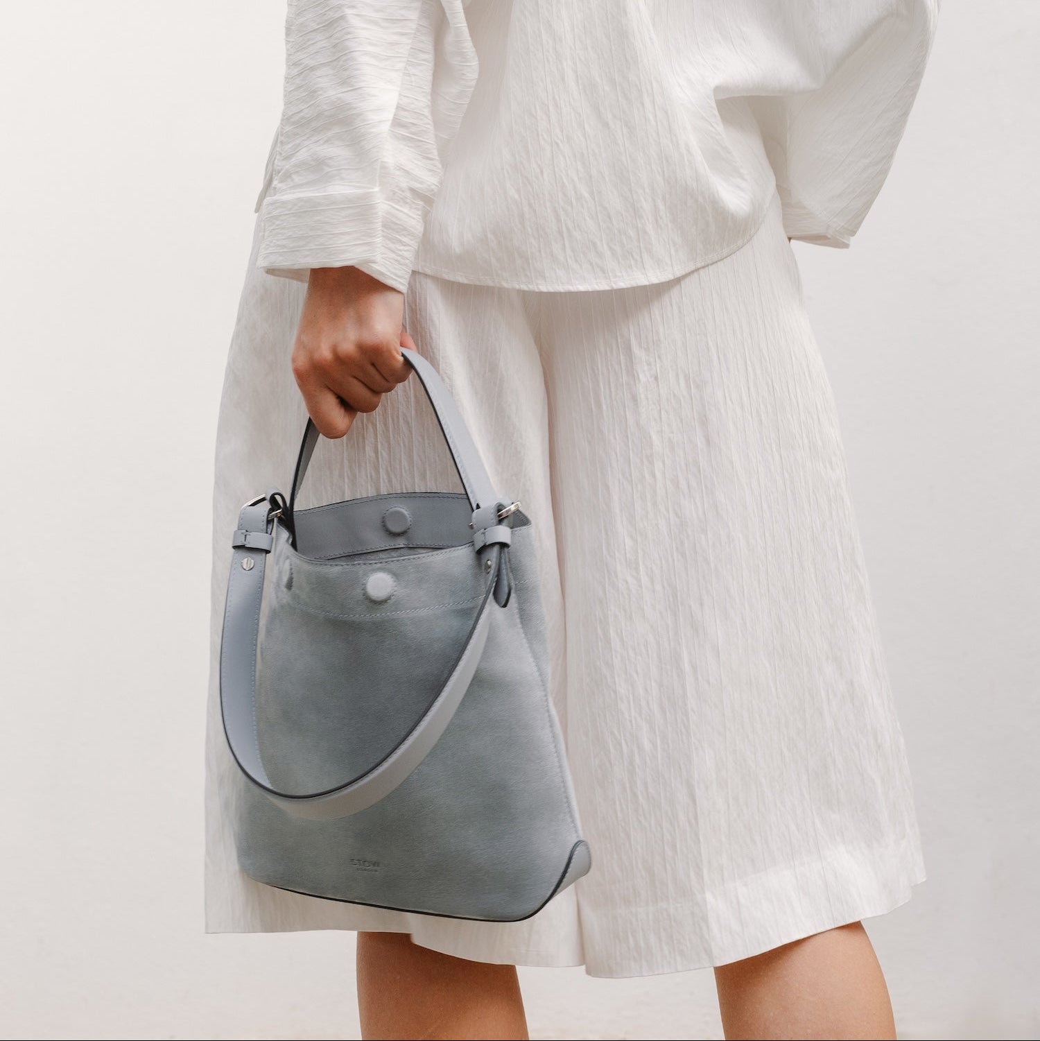 Model with STOW London's Midi Curve in Misty Blue suede featuring the detachable shoulder strap