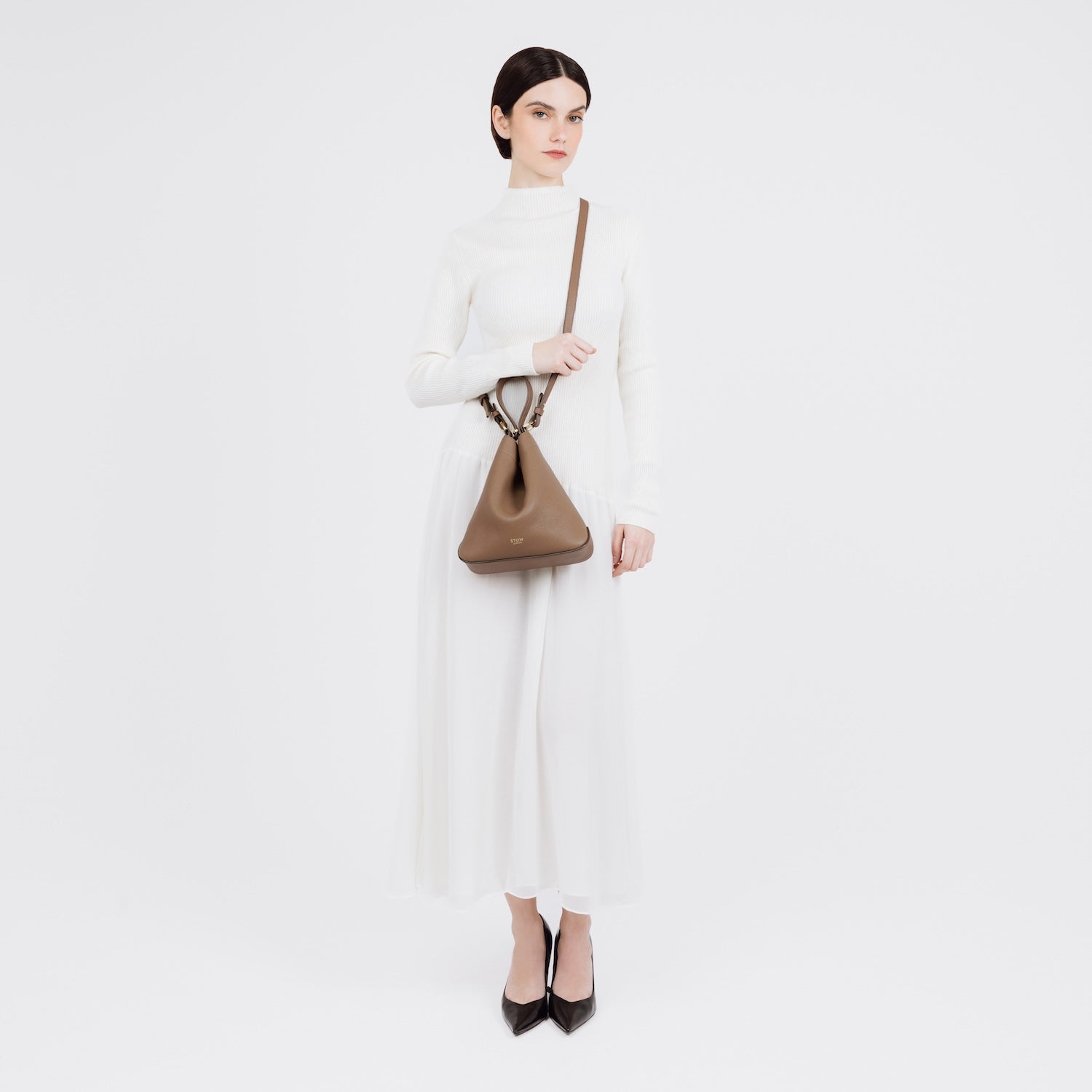 Model wearing STOW London's Midi Curve in Mocha pebbled leather crossbody gold-coated stainless steel hardware