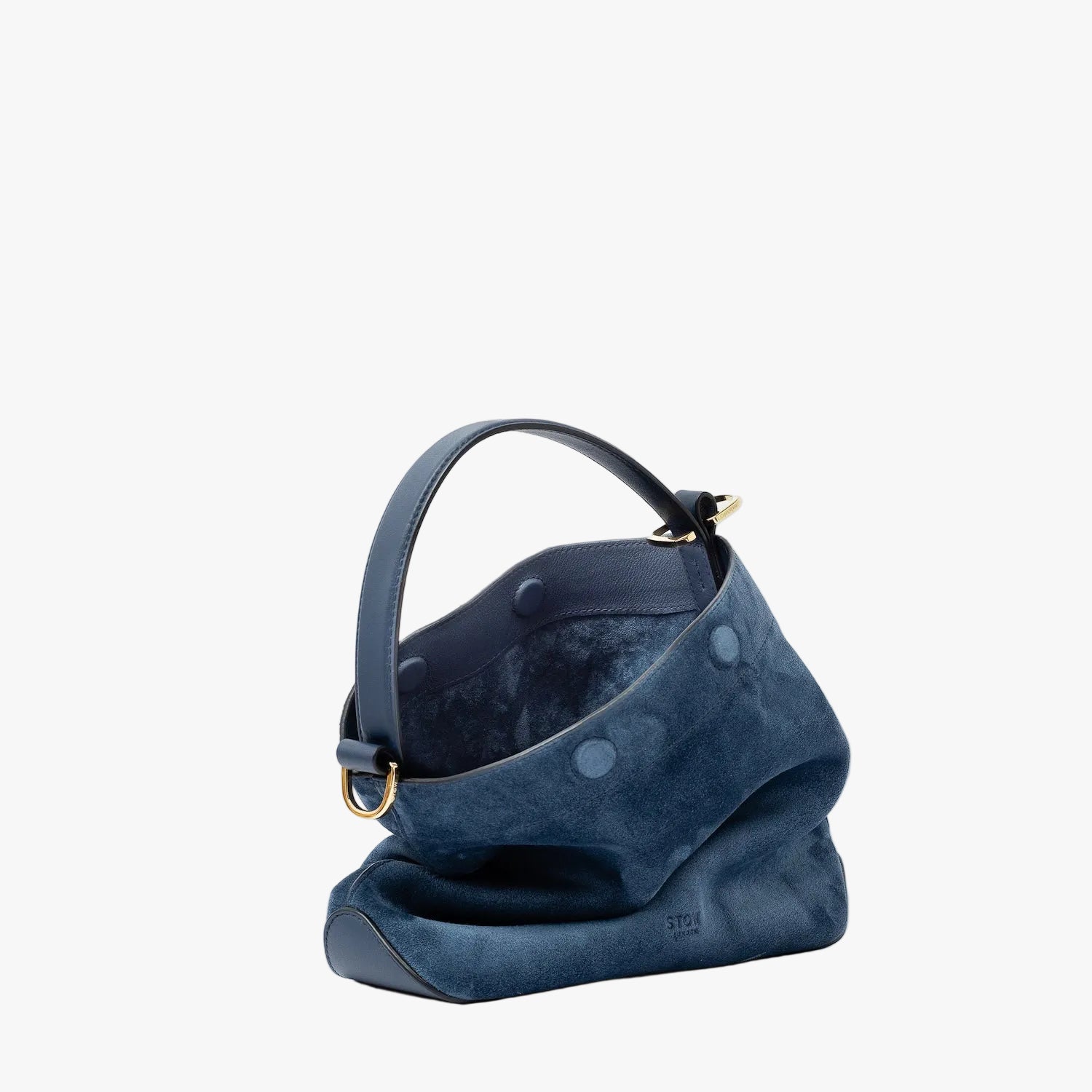 Off-axis view of STOW London's Midi Curve in Navy suede leather with magnets open showing suede interior featuring gold-coated stainless steel hardware on a light grey background