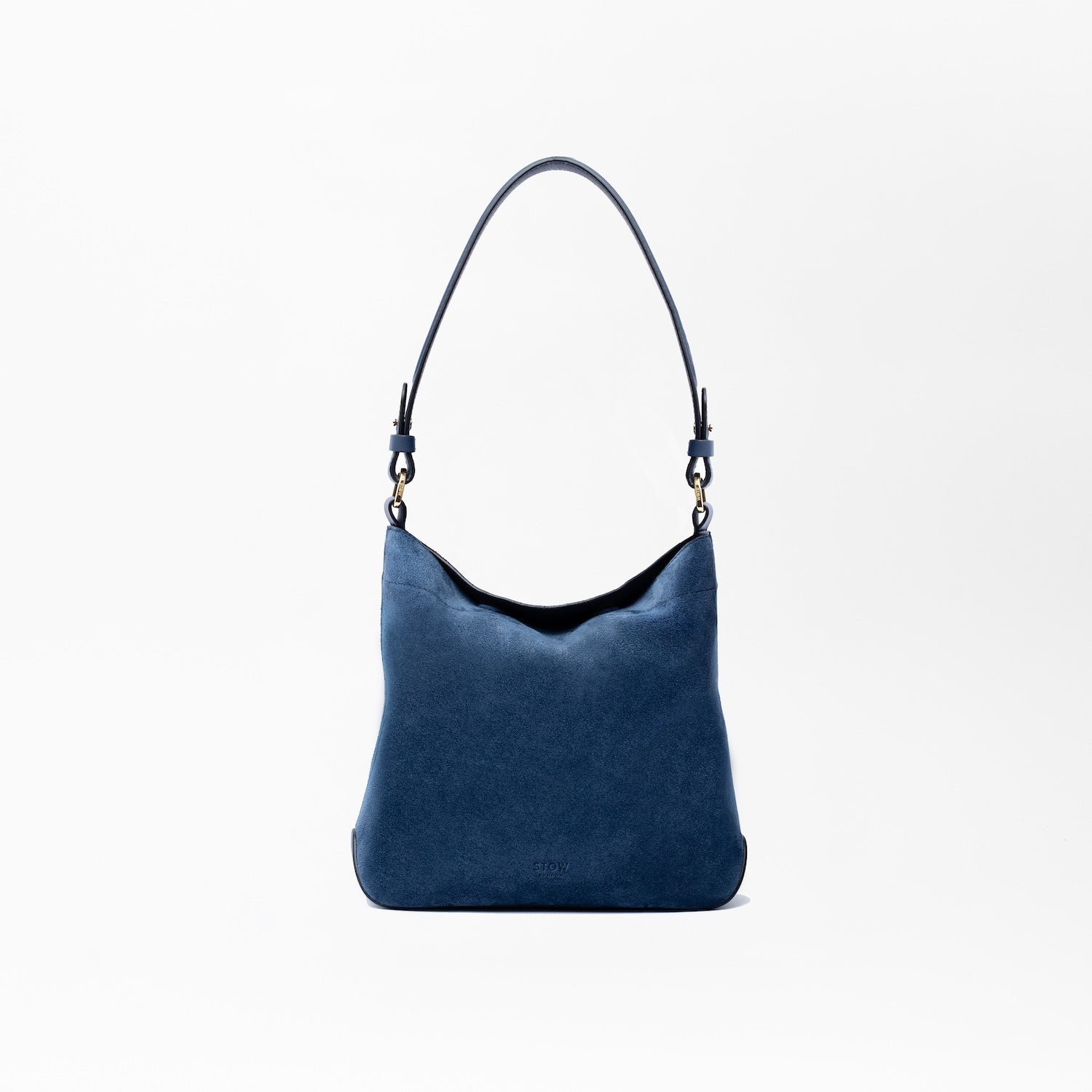 STOW London's Midi Curve in Navy suede leather on a light grey background featuring the detachable shoulder strap with gold hardware and details