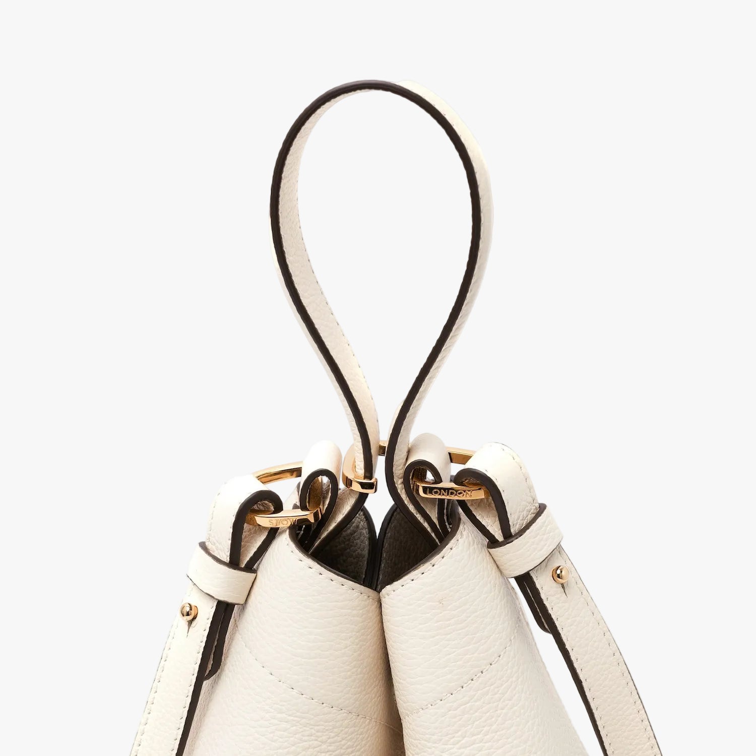 Close up of the handle and detachable crossbody strap attachments of STOW London's Midi Curve in Spring Moon pebbled leather featuring gold-coated stainless steel hardware on a light grey background