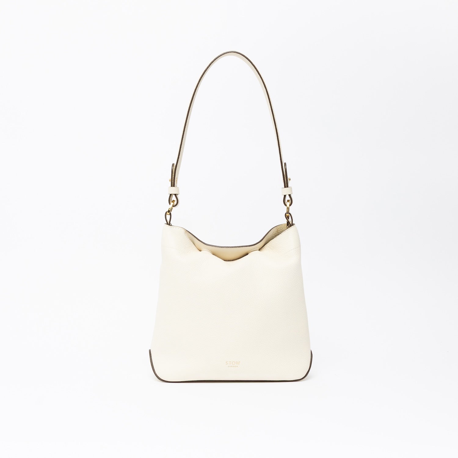 STOW London's Midi Curve in Spring Moon leather on a light grey background featuring the detachable shoulder strap with gold hardware and details