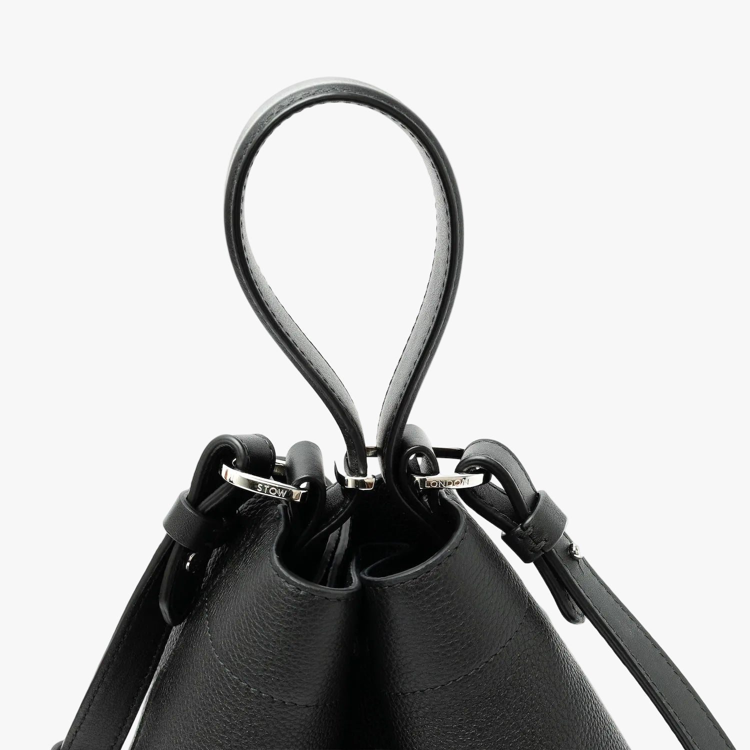 Close up of the handles on STOW London's Midi Curve in Black pebbled leather featuring silver stainless steel hardware, clip and detachable strap on a light grey background