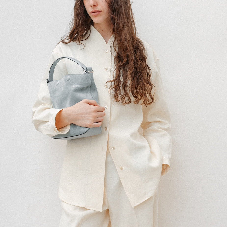 Model holding STOW London's Midi Curve in Misty Blue suede leather featuring silver stainless steel hardware