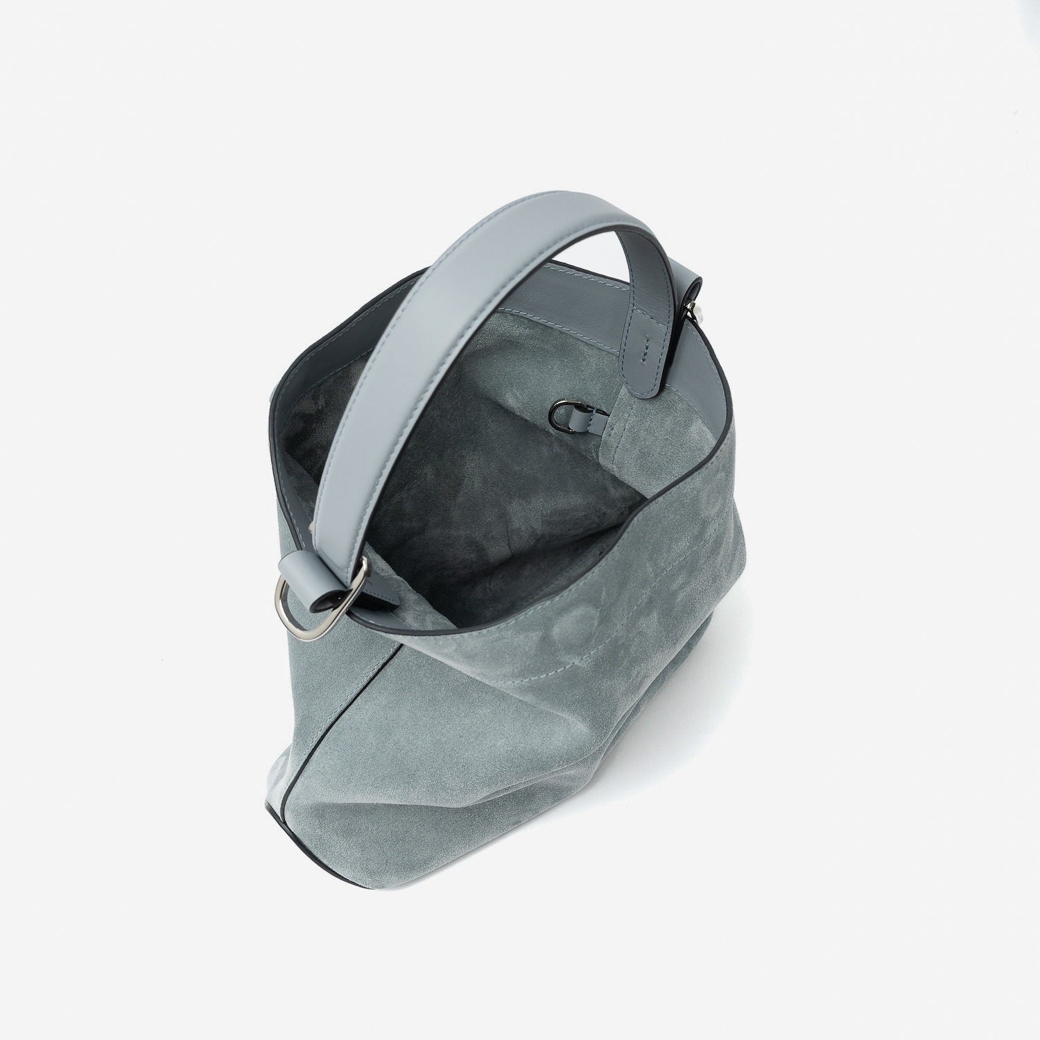 Top angled view of STOW London's Midi Curve in Misty Blue suede leather with magnets open showing suede interior and d-ring featuring silver stainless steel hardware on a light grey background