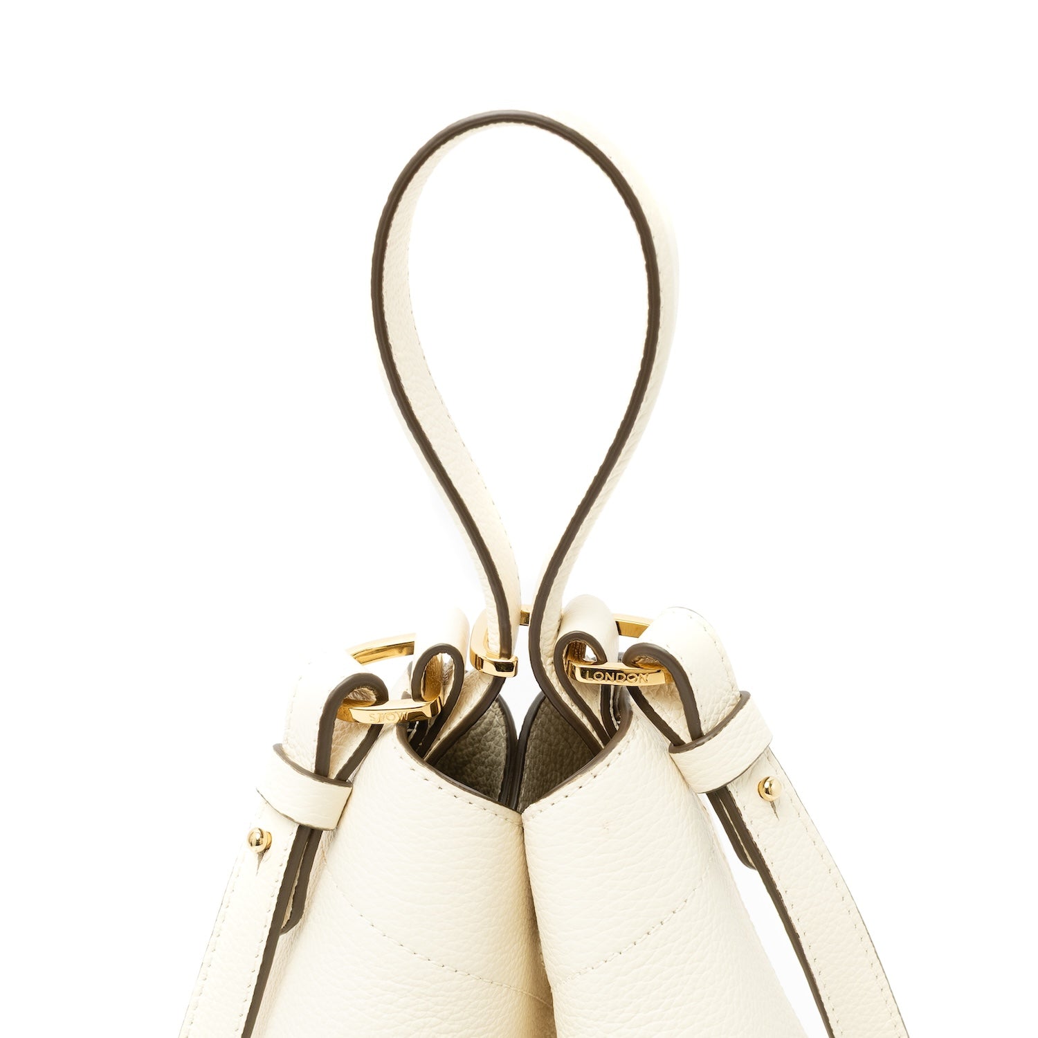 Close up of top handle, clip and detachable strap on STOW London's Midi Curve bag in Spring Moon pebbled and smooth leather featuring gold-coated stainless steel hardware on a white background