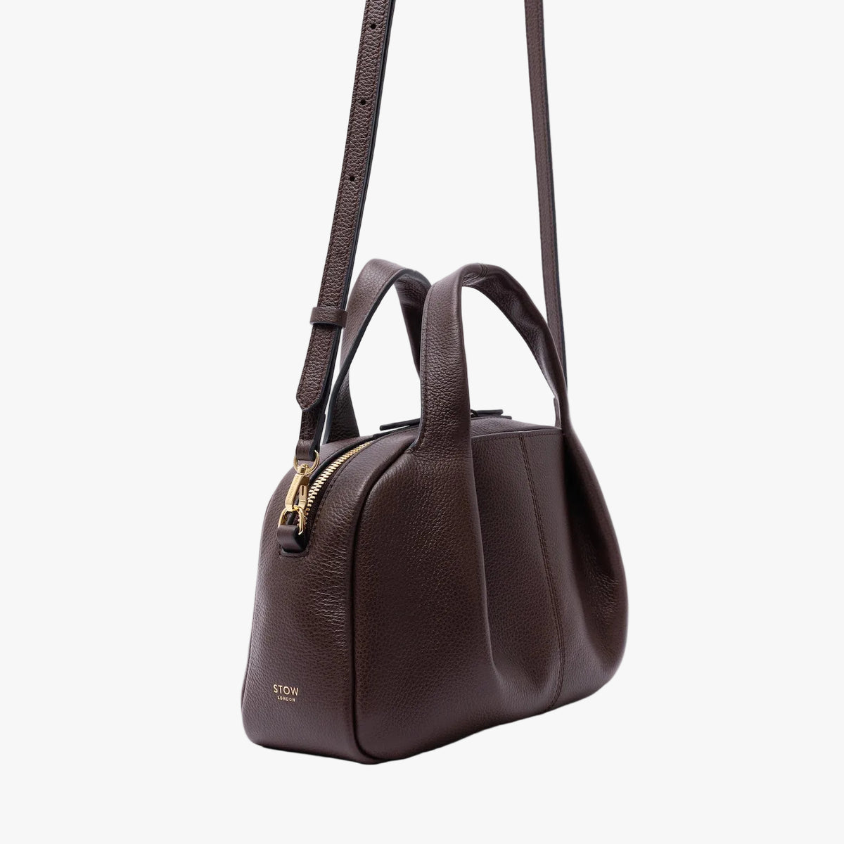 Off-axis shot of STOW London's Mini Bowling in Espresso pebbled leather on a light grey background featuring gold-coated stainless steel hardware and the detachable crossbody strap