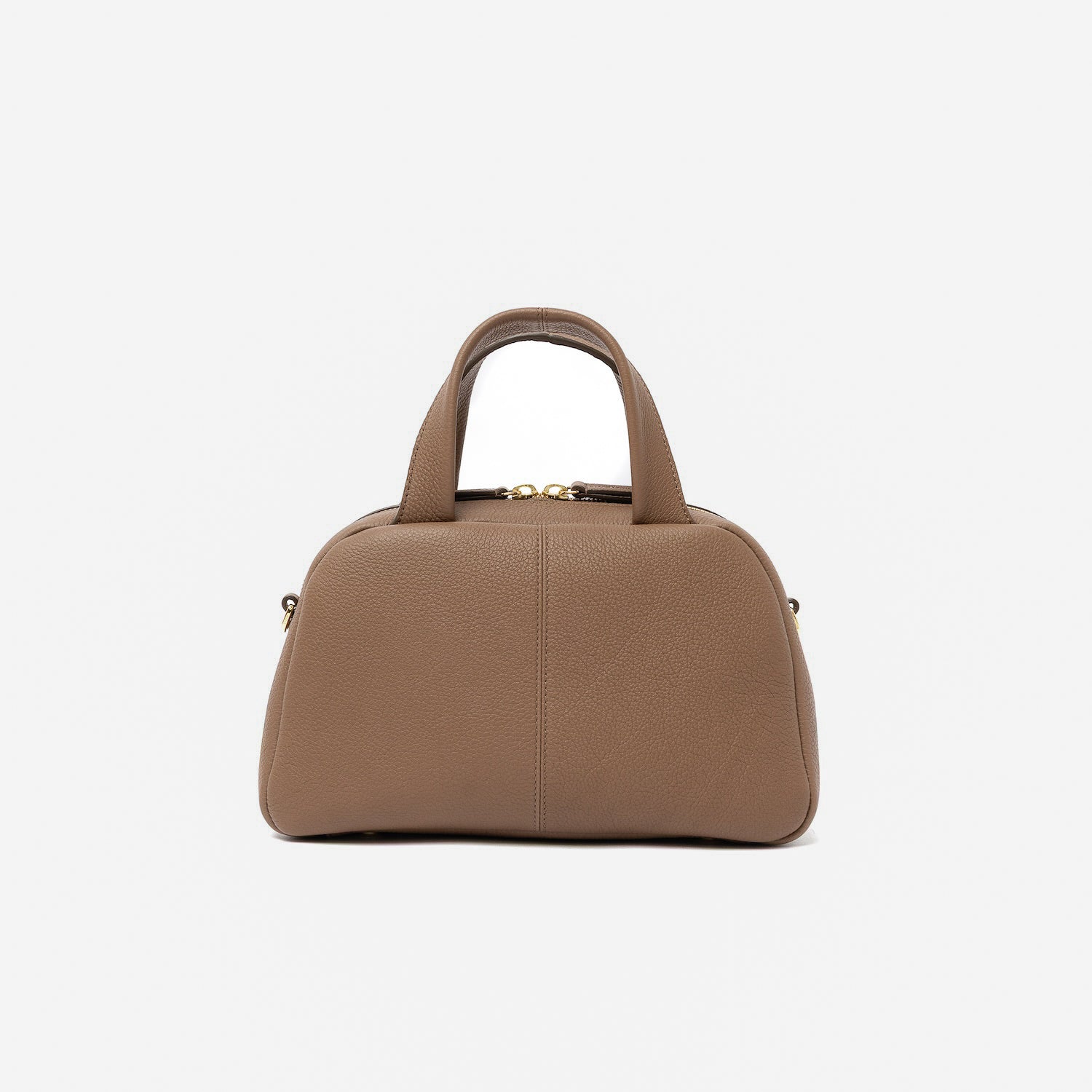 Back panel of STOW London's Mini Bowling bag in Mocha pebbled leather featuring gold-coated stainless steel hardware and four feet on the base on a light grey background