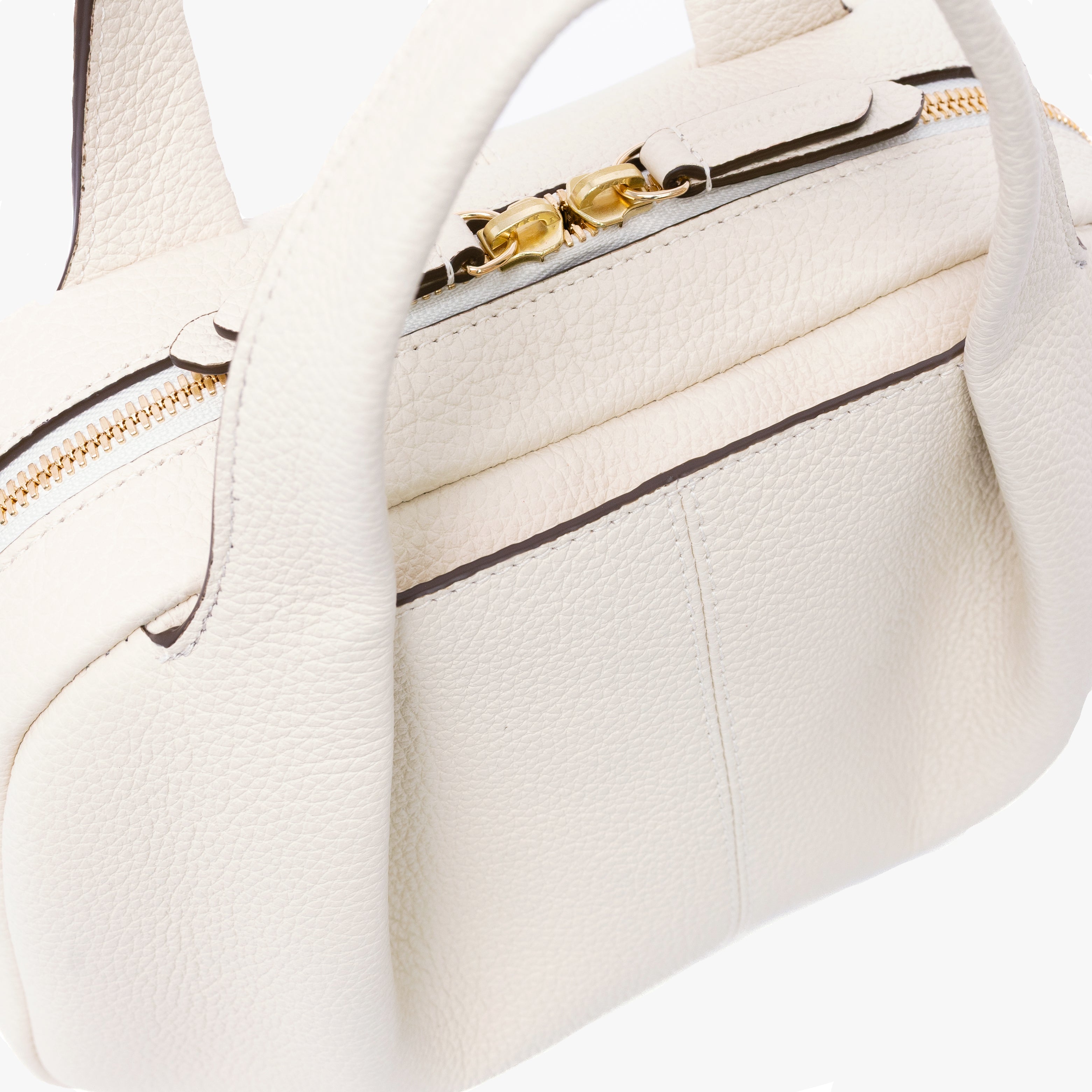 Close up of STOW London's Mini Bowling bag in Spring Moon pebbled leather featuring a pleated front panel and gold-coated stainless steel hardware on a light grey background