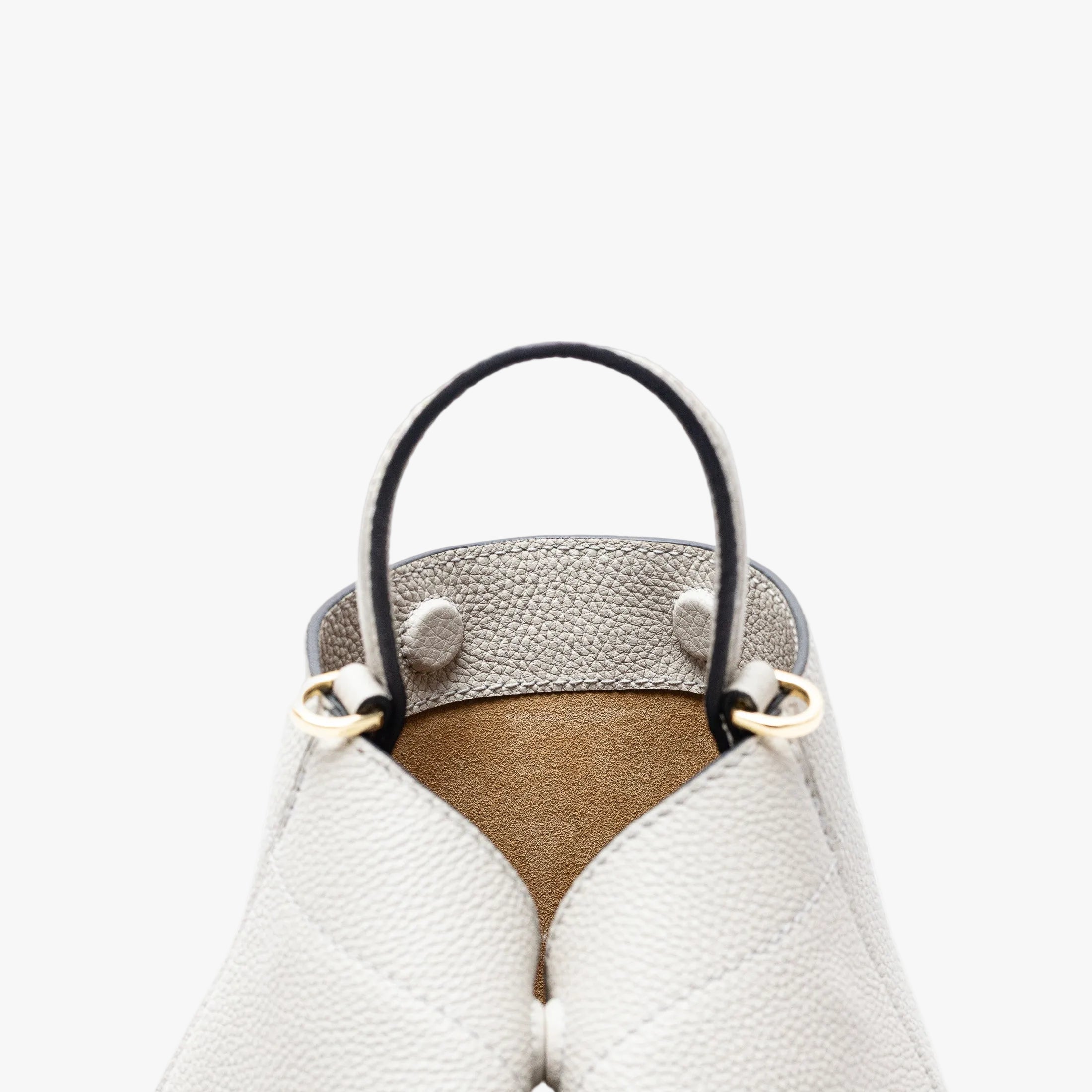 Close up of the top of Stow London's Mini Curve in Cloud Grey pebbled leather featuring the hidden magnets, suede lining and gold hardware on a light grey background
