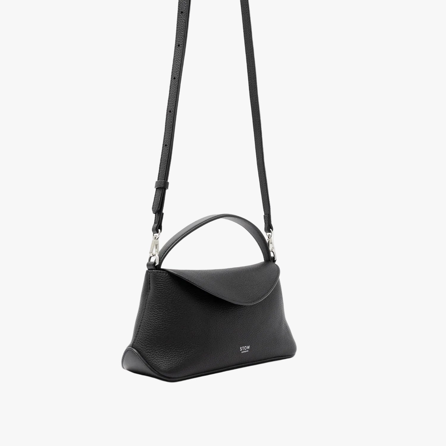 Off-axis view of STOW London's Mini East West in Black pebbled leather and detachable crossbody strap featuring silver stainless steel hardware on a light grey background