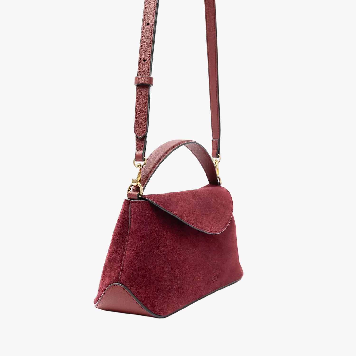 Off-axis view of STOW London's Mini East West in Burgundy suede leather and detachable crossbody strap featuring gold-coated stainless steel hardware on a light grey background