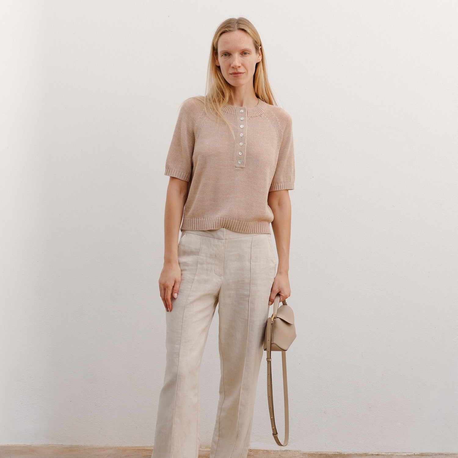 Model holding STOW London's Mini East West in Camel pebbled leather featuring gold-coated stainless steel hardware