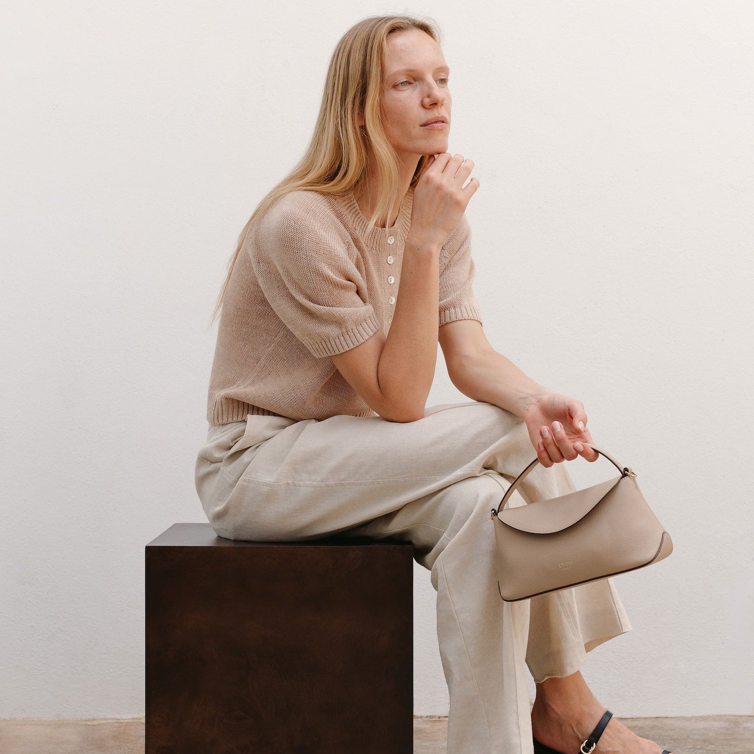 Model sat with STOW London's Mini East West in Camel pebbled leather featuring gold-coated stainless steel hardware