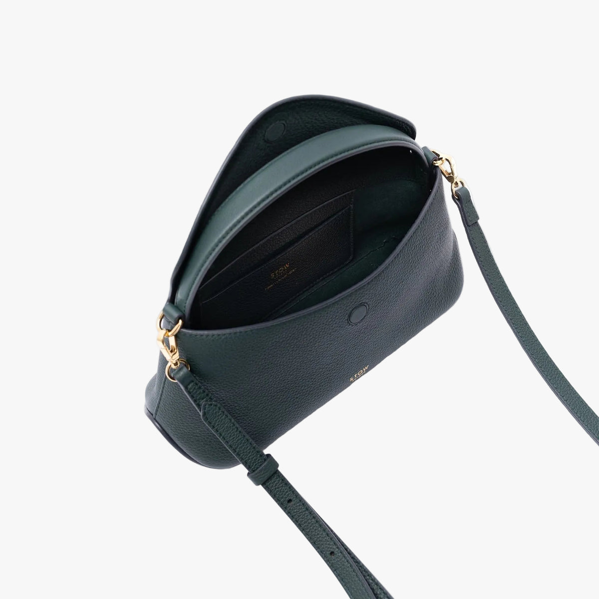 Top view of STOW London's Mini East West in New Forest pebbled leather on a light grey background with the flap open showing the suede interior lining and leather slip pocket
