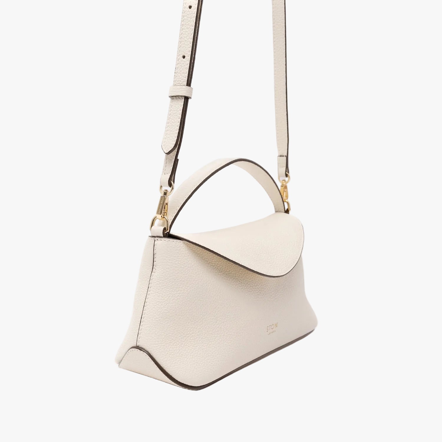 Off-axis view of STOW London's Mini East West in Spring Moon pebbled leather and detachable crossbody strap featuring gold-coated stainless steel hardware on a light grey background