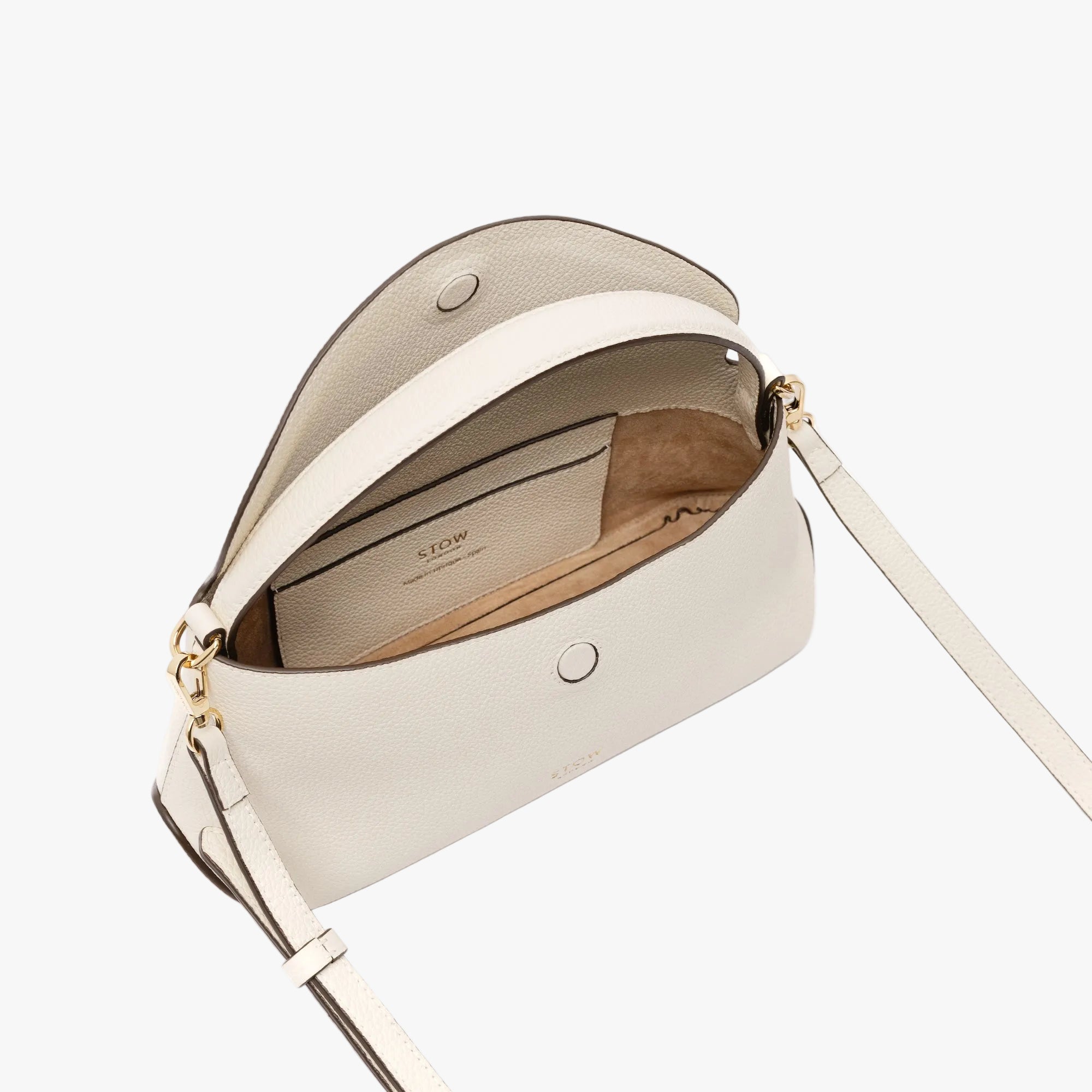 Overhead shot of STOW London's Mini East West in Spring Moon pebbled leather with flap open showing suede interior and leather slip pocket featuring gold-coated stainless steel hardware on a light grey background
