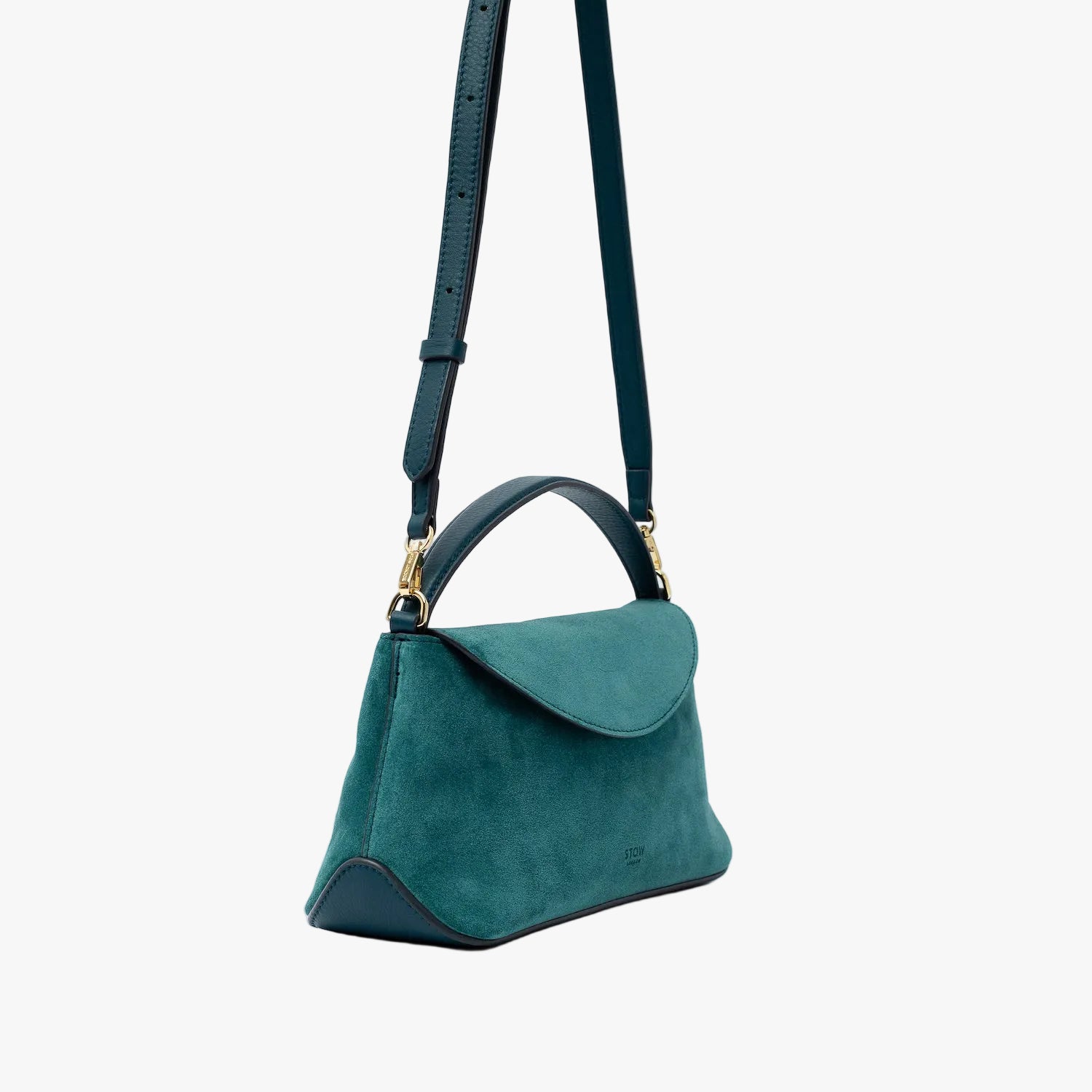 Off-axis view of STOW London's Mini East West in Ocean Teal suede leather and detachable crossbody strap featuring gold-coated stainless steel hardware on a light grey background