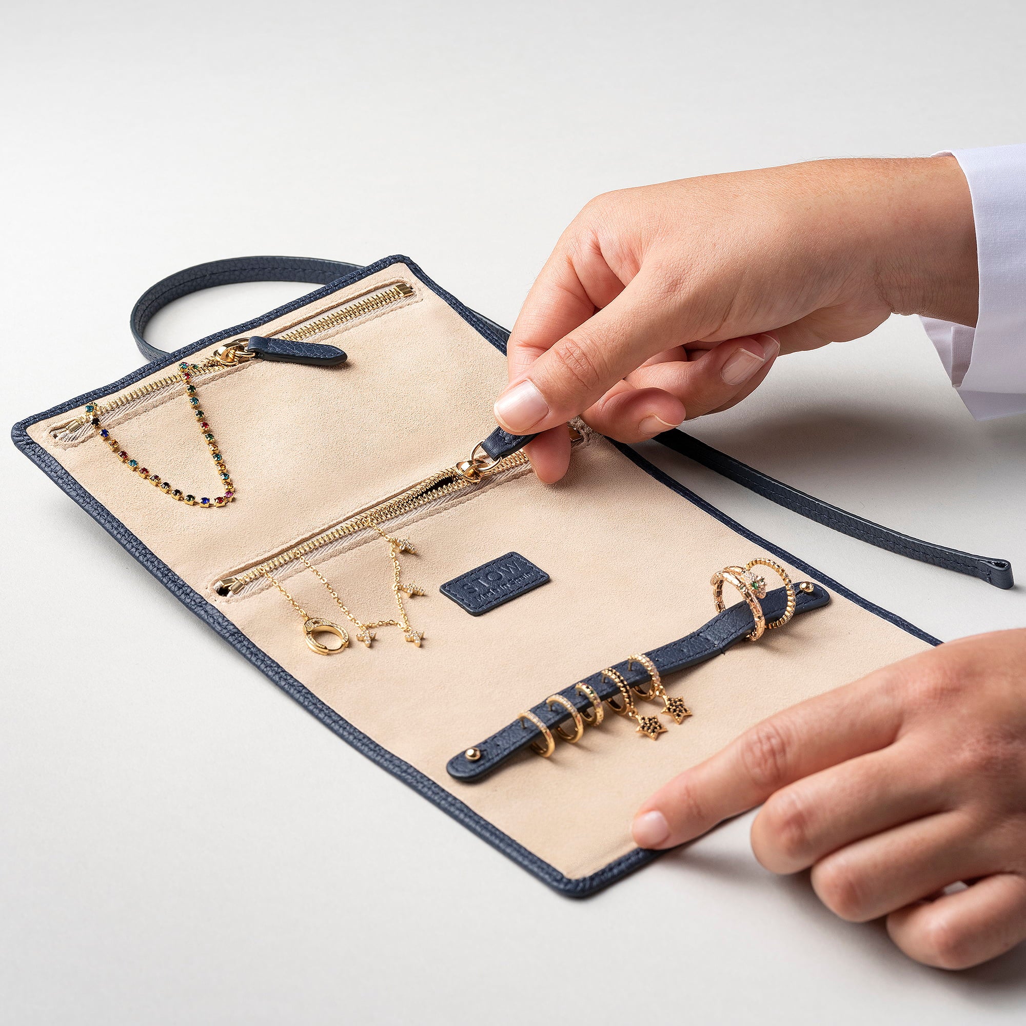 STOW London Mini Jewellery Roll in Navy leather, open showing zipped pockets and suede lining.