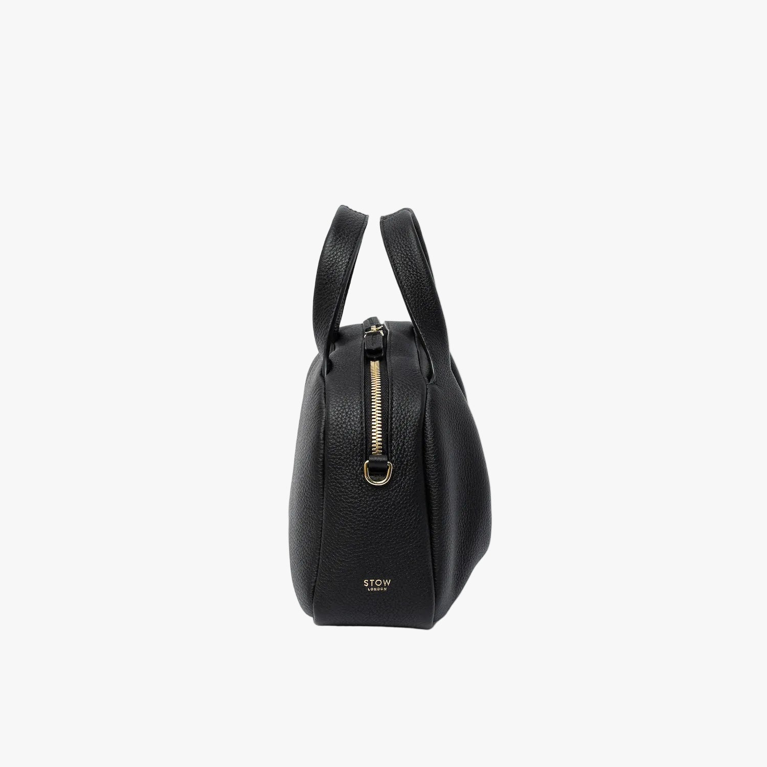 Side view of STOW London's Mini Bowling bag in Black pebbled leather featuring the zip closure, gold-coated stainless steel hardware and small logo on a light grey background