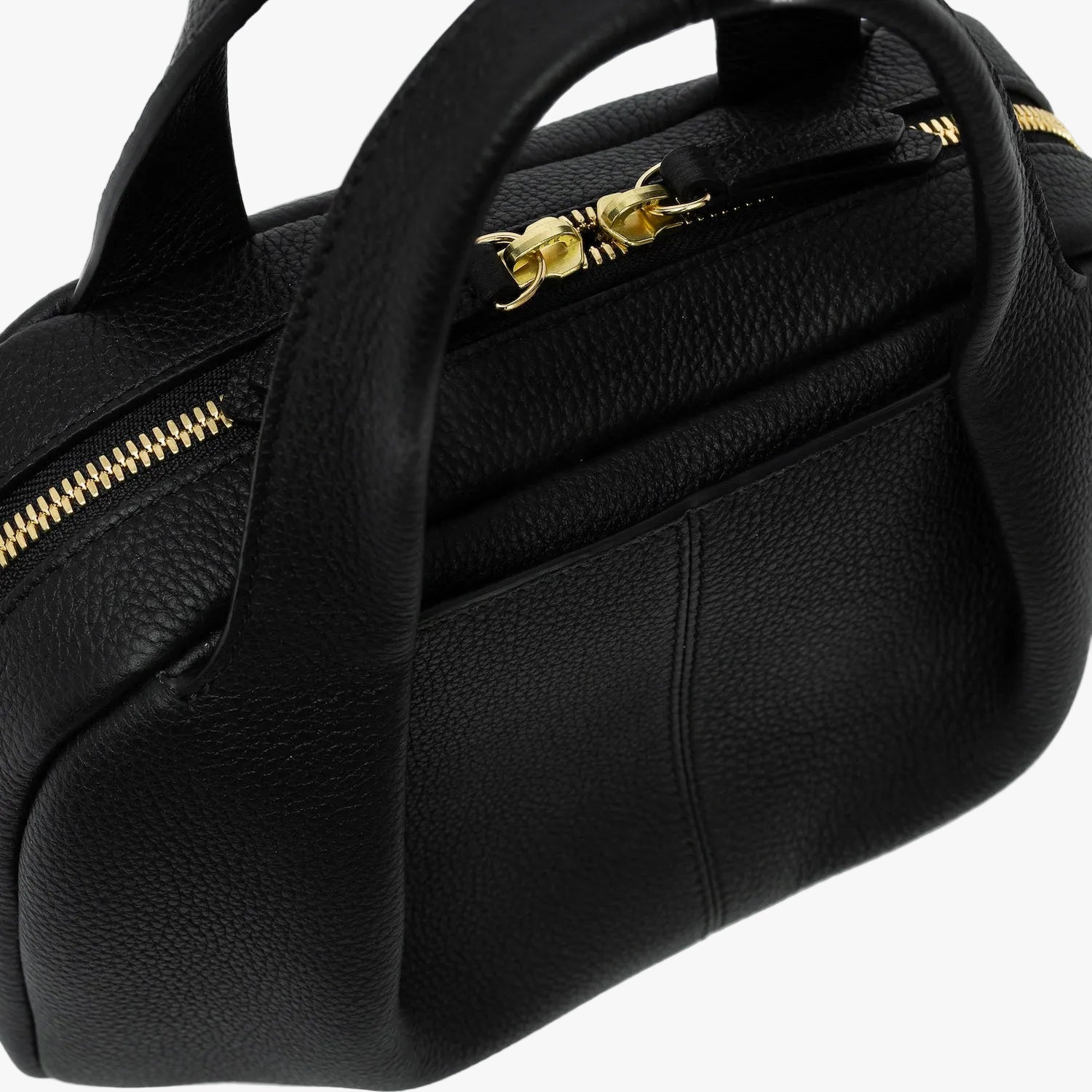 Close up of STOW London's Mini Bowling bag in Black pebbled leather featuring a pleated front panel with the external slip pocket in-between, zip closure, STOW London embossed pull tabs and gold-coated stainless steel hardware on a light grey background