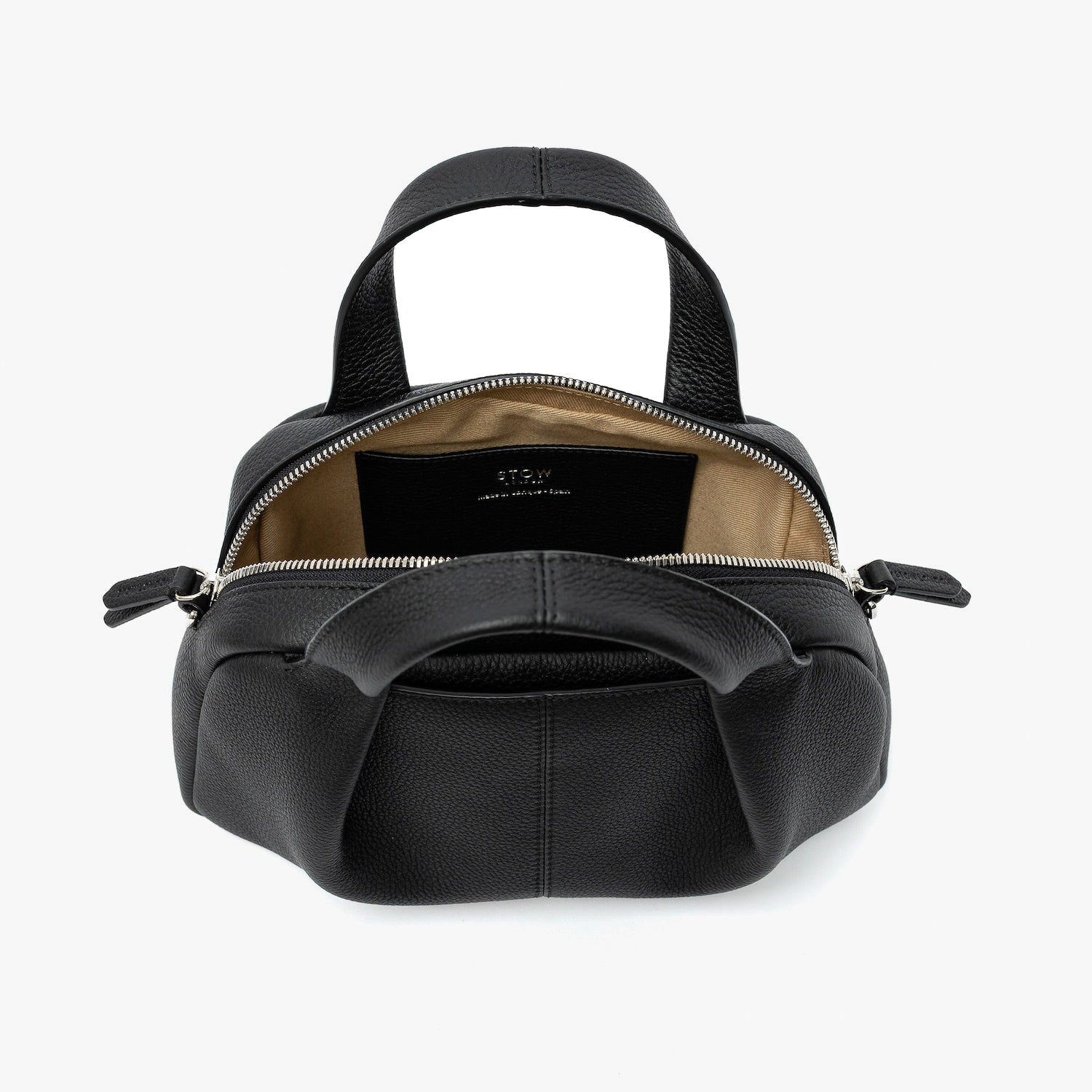 STOW London's Mini Bowling bag in Black pebbled leather with zips open showing the light beige cotton interior lining and slip pocket featuring silver stainless steel hardware on a light grey background