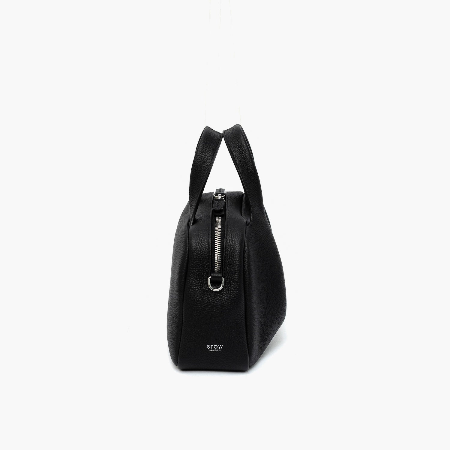 Side view of STOW London's Mini Bowling bag in Black pebbled leather featuring a silver stainless steel hardware, zip and small logo on a light grey background