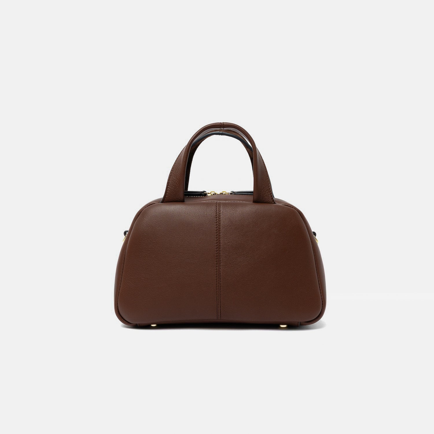Smooth leather back panel of STOW London's Mini Bowling bag in Chocolate leather featuring gold-coated stainless steel hardware and four feet on the base on a light grey background