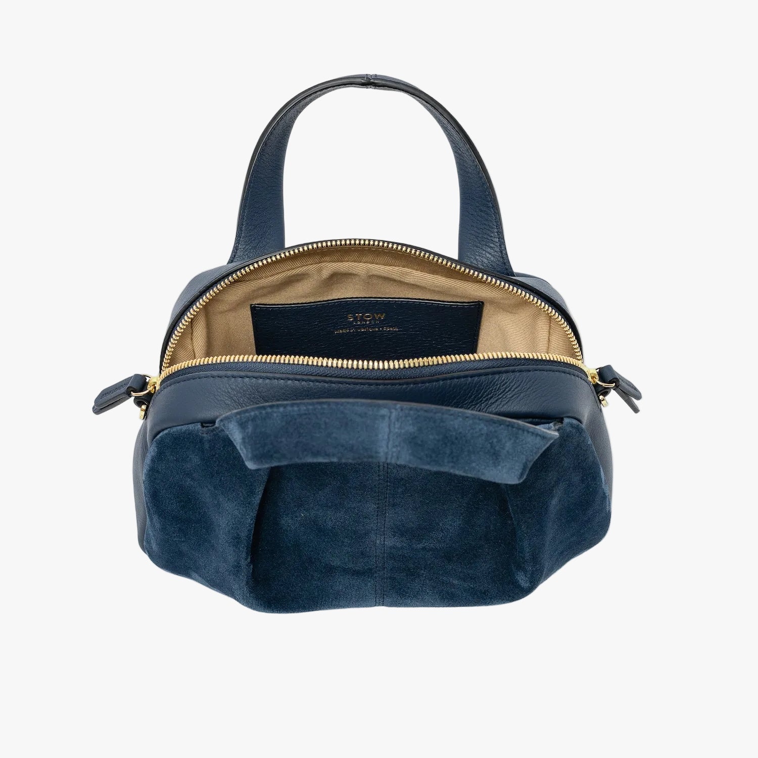 STOW London's Mini Bowling bag in Navy suede and smooth leather with zipper open showing the cotton interior lining and the internal slip pocket featuring gold-coated stainless steel hardware on a light grey background