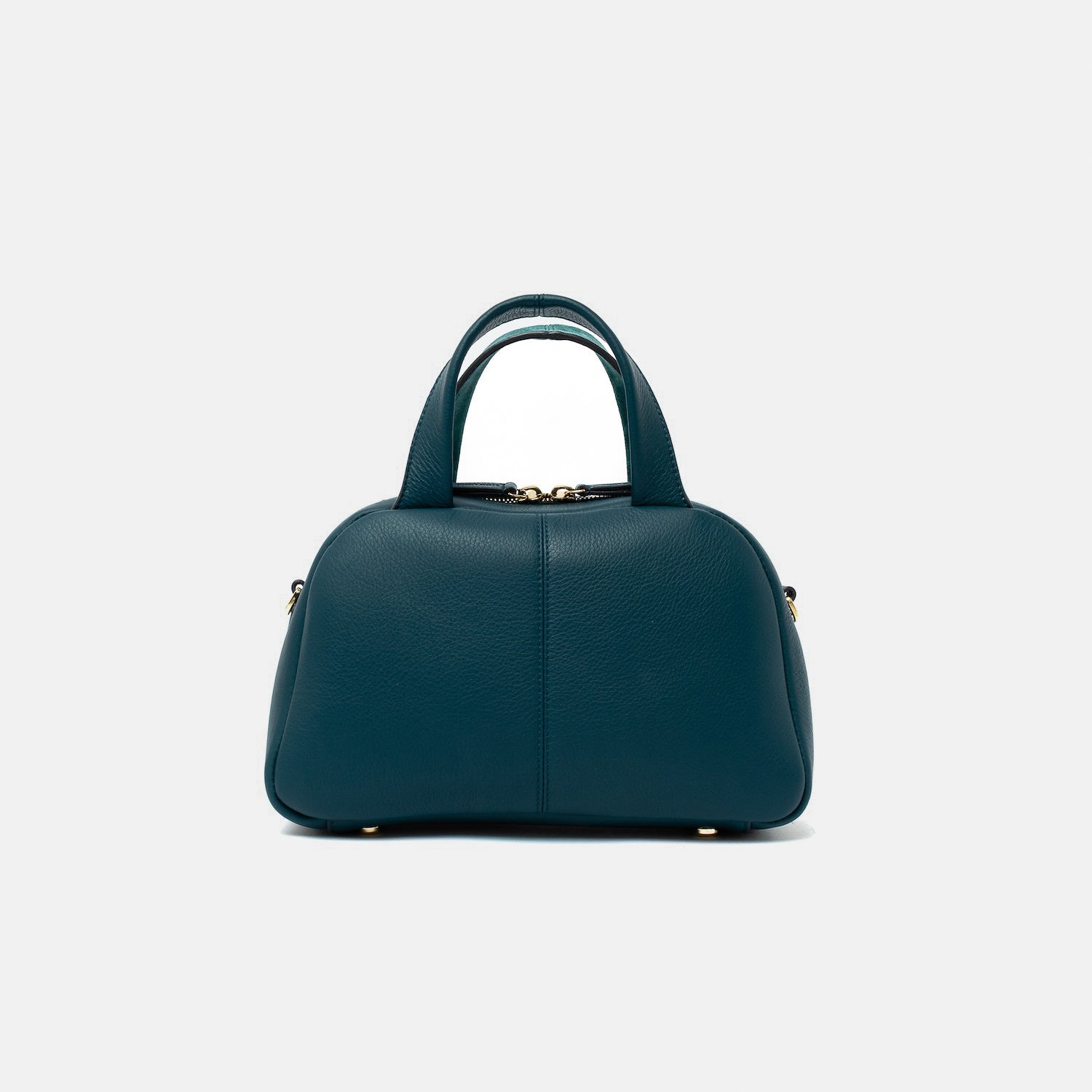 Smooth leather back panel of STOW London's Mini Bowling bag in Ocean Teal leather featuring four feet on the base and gold-coated stainless steel hardware on a light grey background