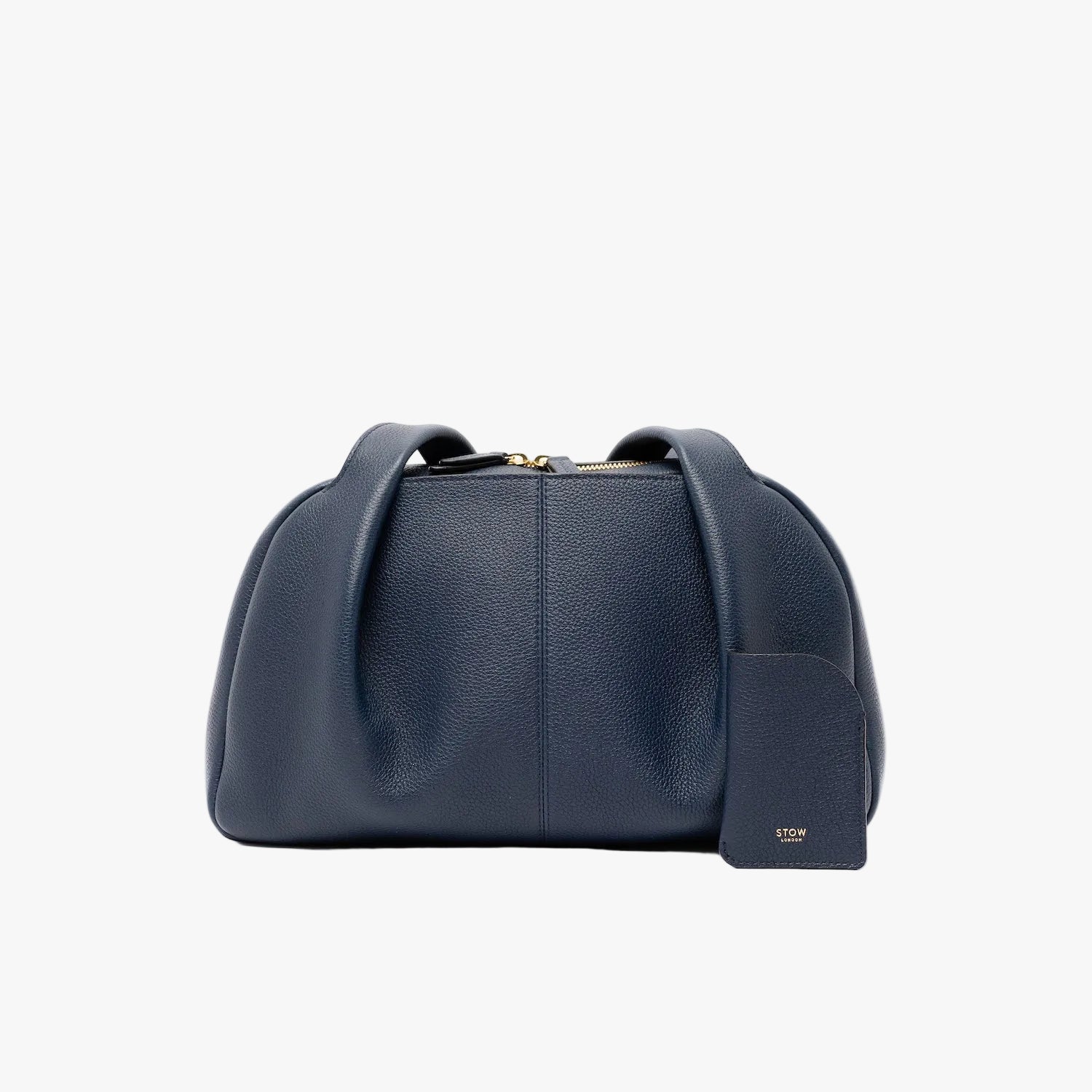 STOW London's Mini Cardholder in Navy pebbled leather with the matching Bowling Bag on a light grey background featuring a small gold embossed logo on the front bottom