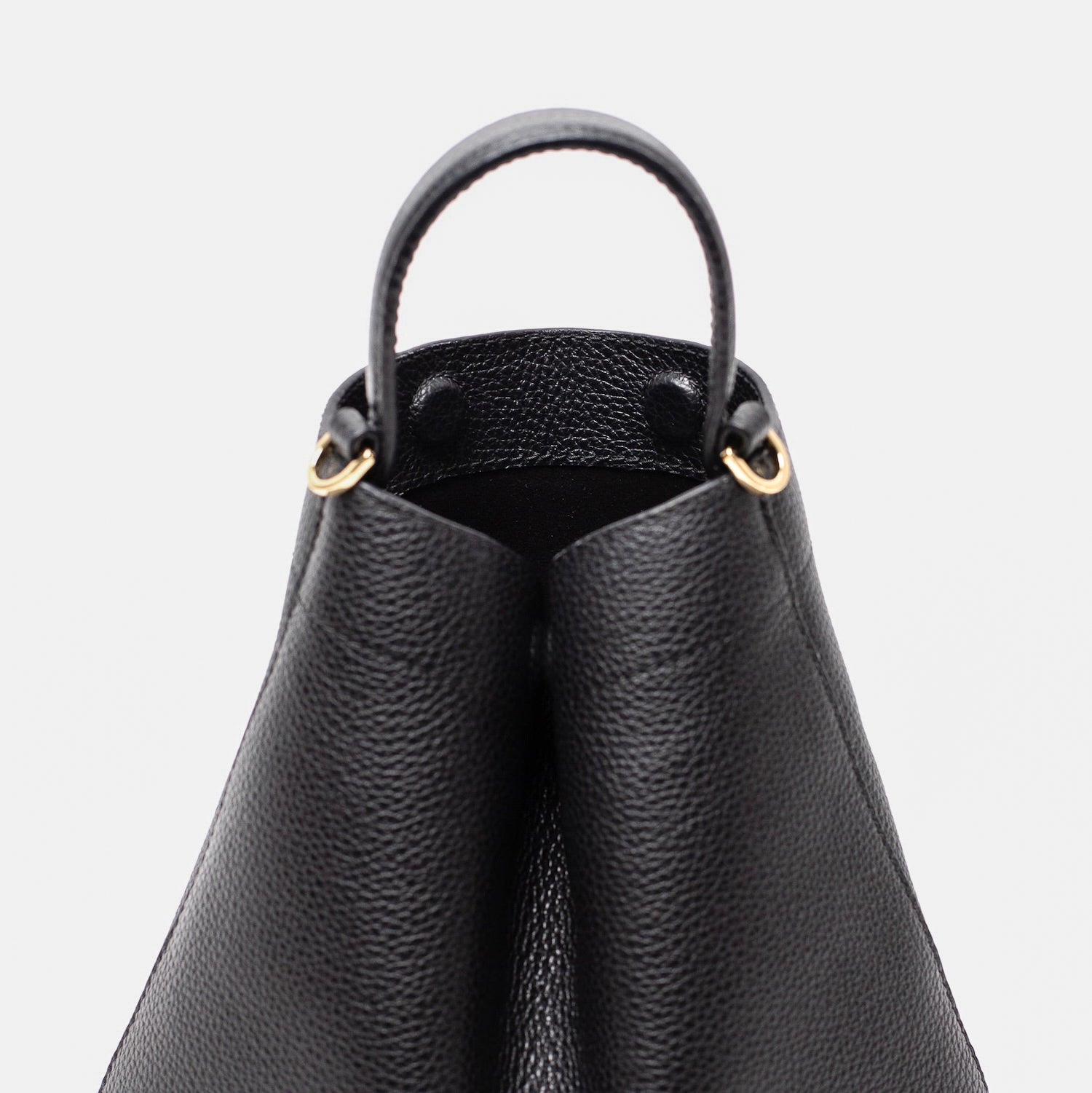 Close up of STOW London's Mini Curve in Black pebbled leather featuring hidden magnets, suede lining and gold hardware on a light grey background