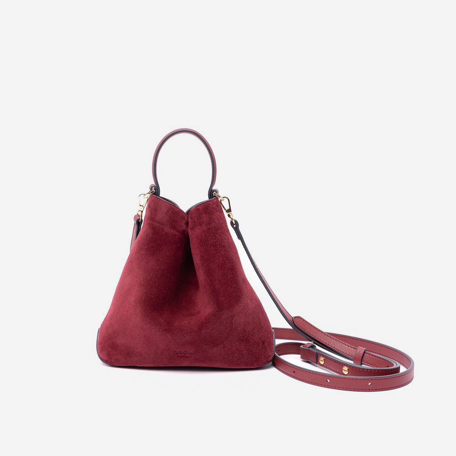 STOW London's Mini Curve in Burgundy suede leather and detachable leather crossbody strap on a light grey background
