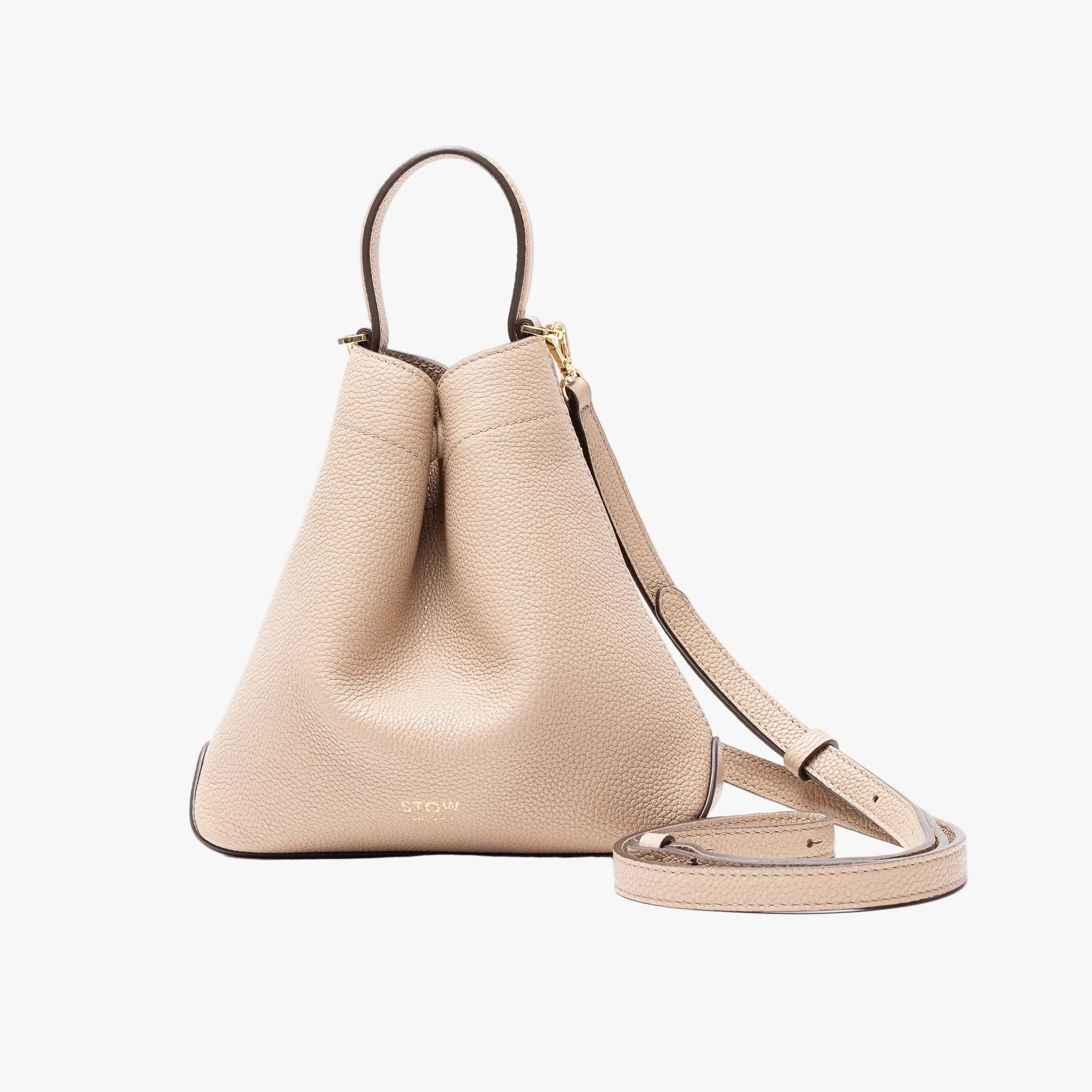STOW London's Mini Curve in Camel pebbled leather and detachable leather crossbody strap on a light grey background