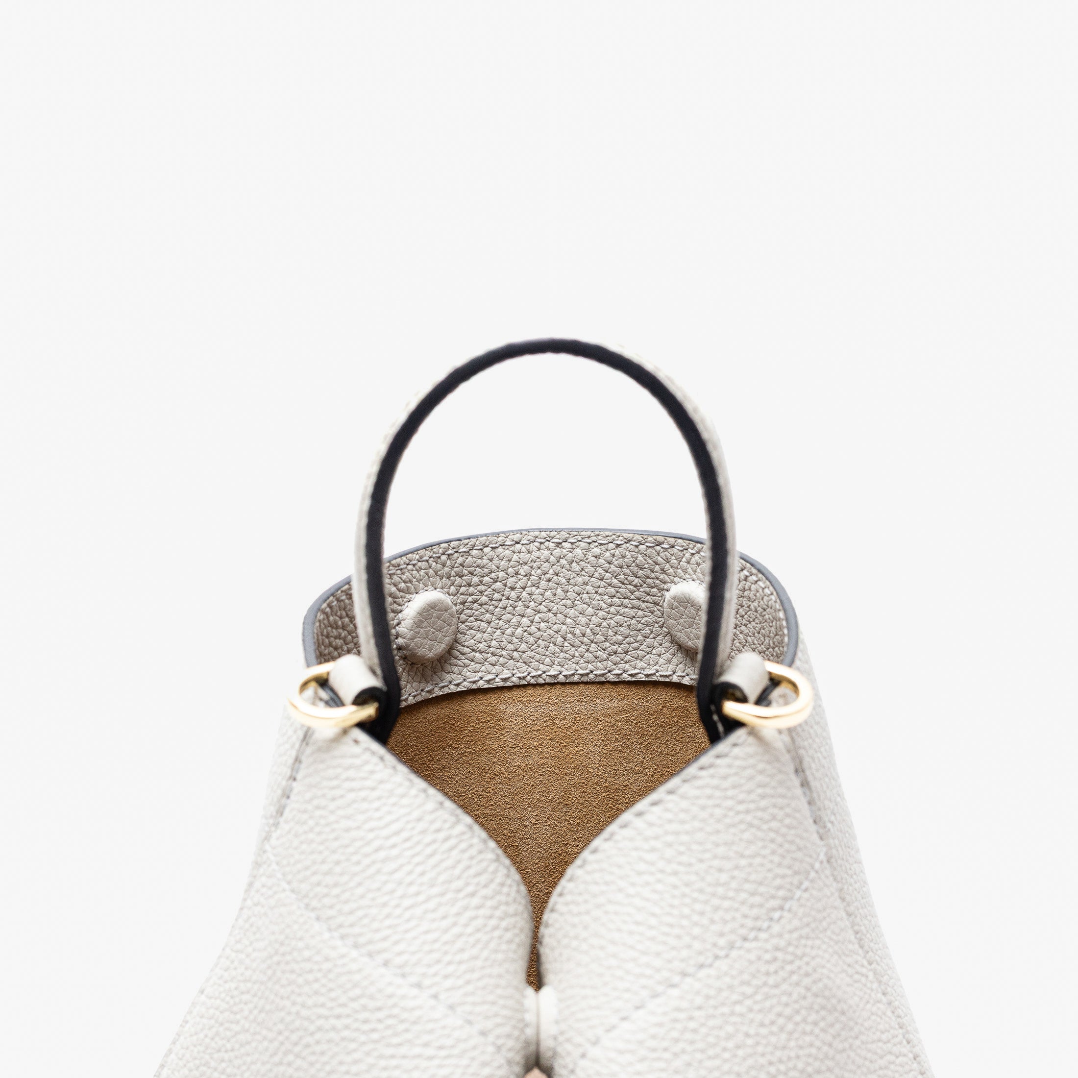 Close up of the top of Stow London's Mini Curve in Cloud Grey pebbled leather featuring the hidden magnets, suede lining and gold hardware on a light grey background