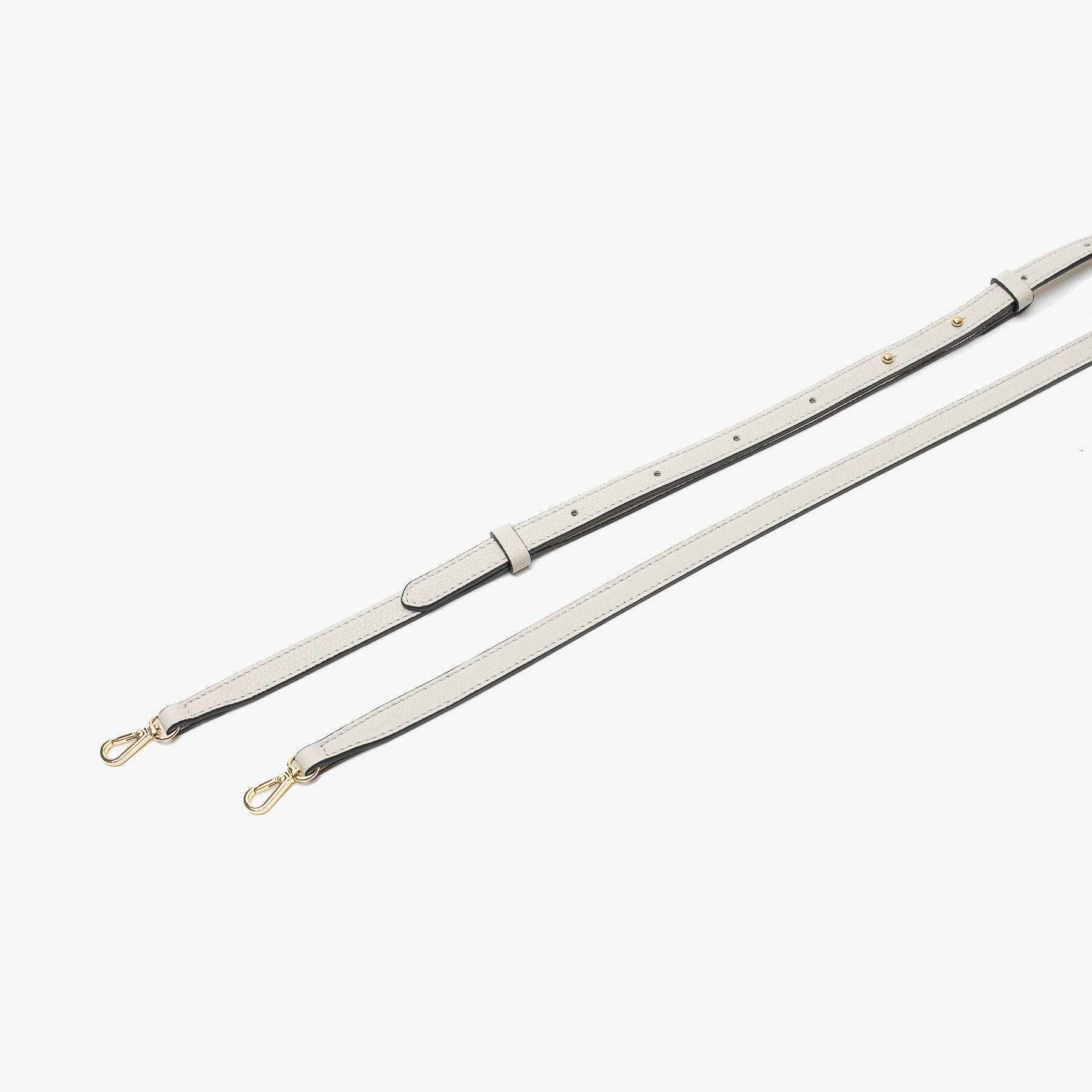 Close up of the detachable leather crossbody strap for STOW London's Mini Curve in Cloud Grey pebbled leather on a light grey background