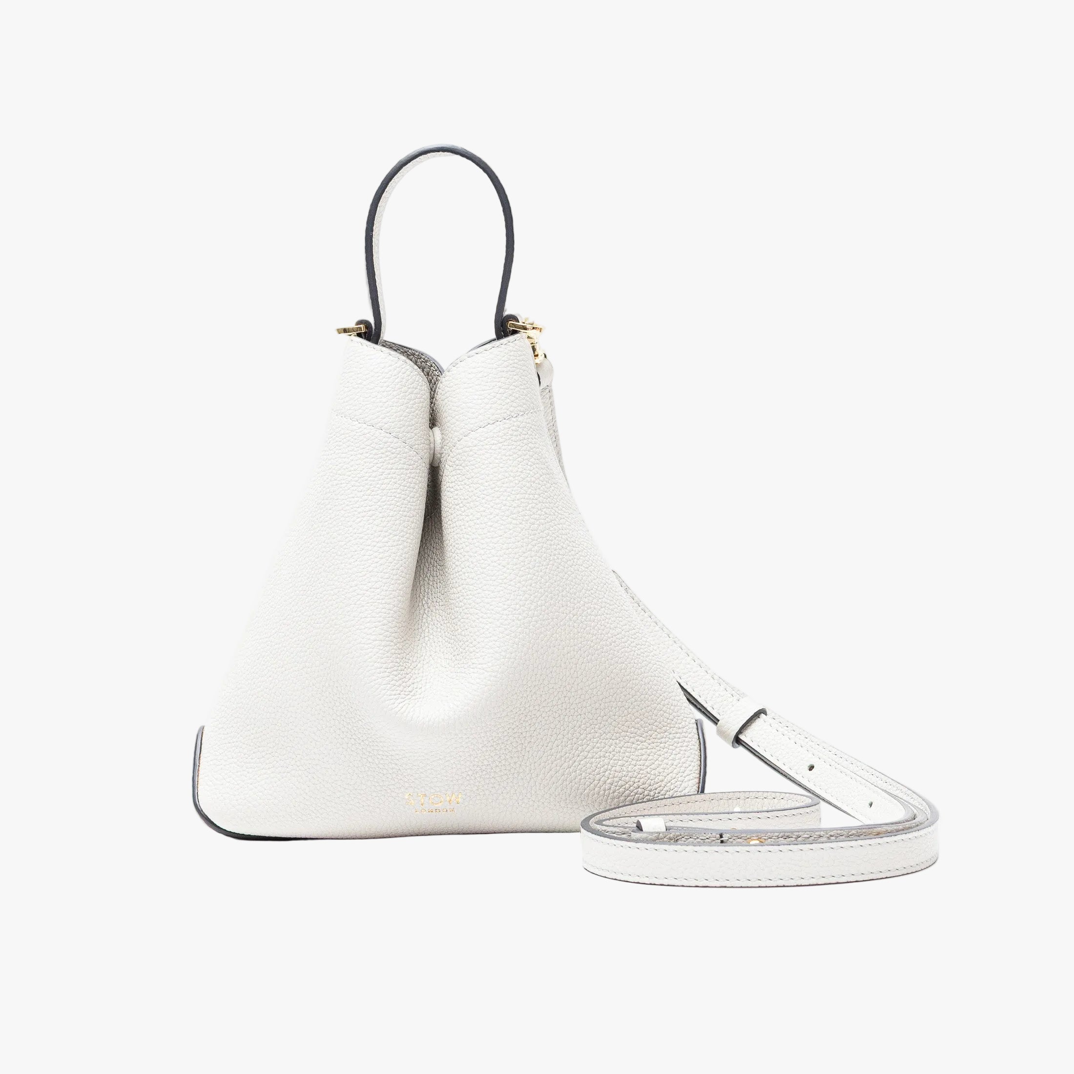 STOW London's Mini Curve in Cloud Grey pebbled leather and detachable leather crossbody strap on a light grey background