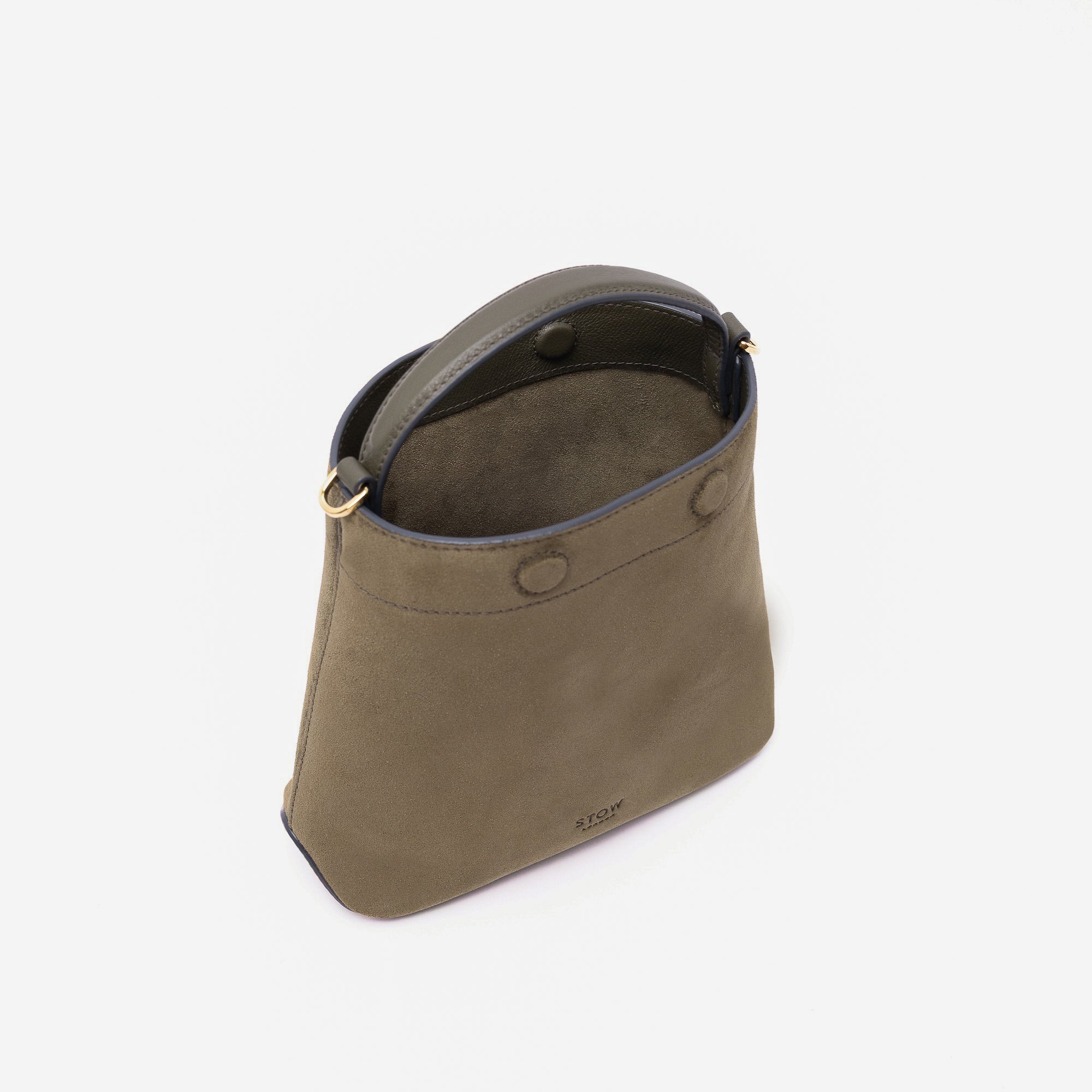 Stow London's Mini Curve in Dark Green suede leather with magnets open styled as a bucket bag featuring soft suede interior and gold-coated stainless steel hardware on a light grey background