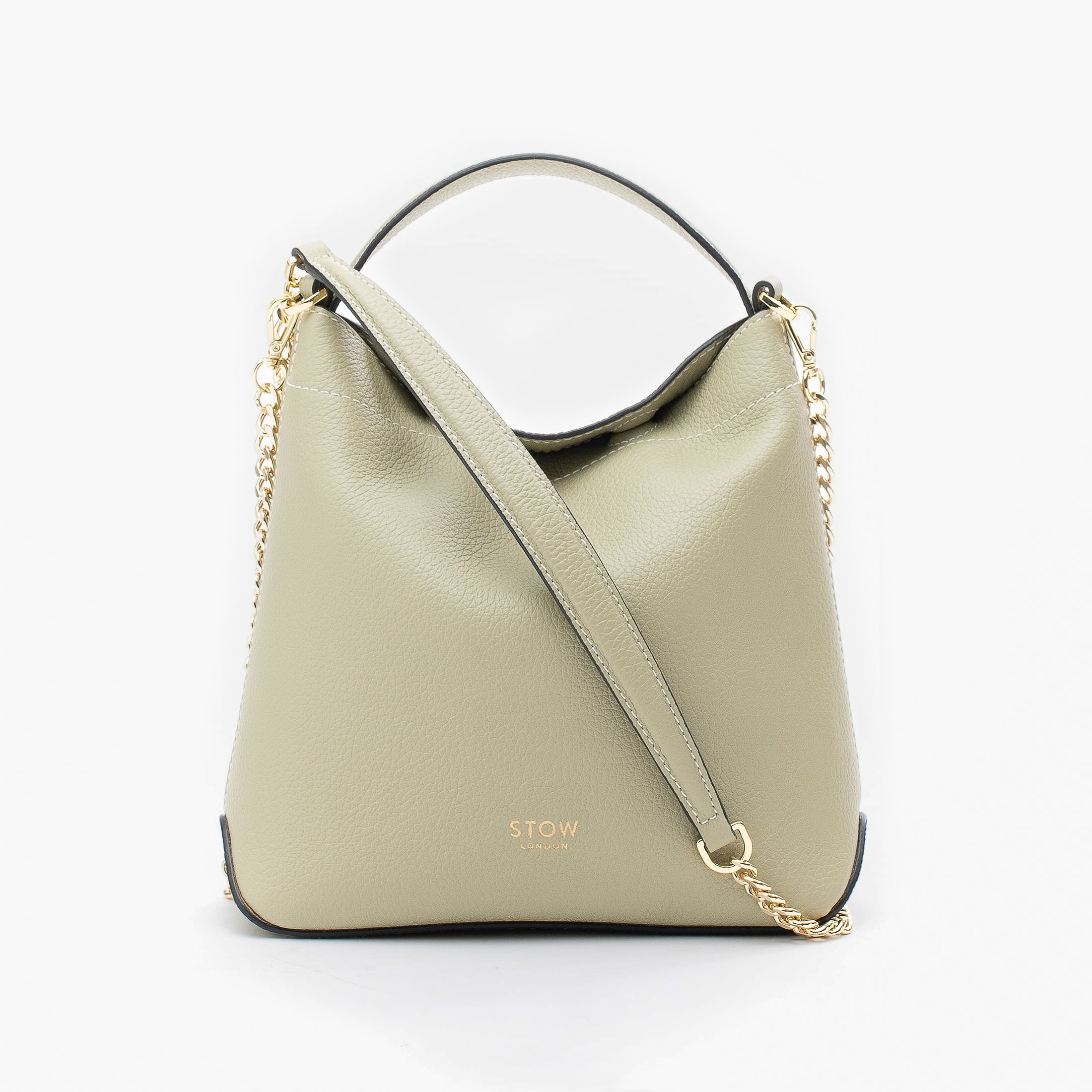 STOW London's Mini Curve in Pale Green pebbled leather and detachable gold chain crossbody strap styled as a flap bag on a light grey background