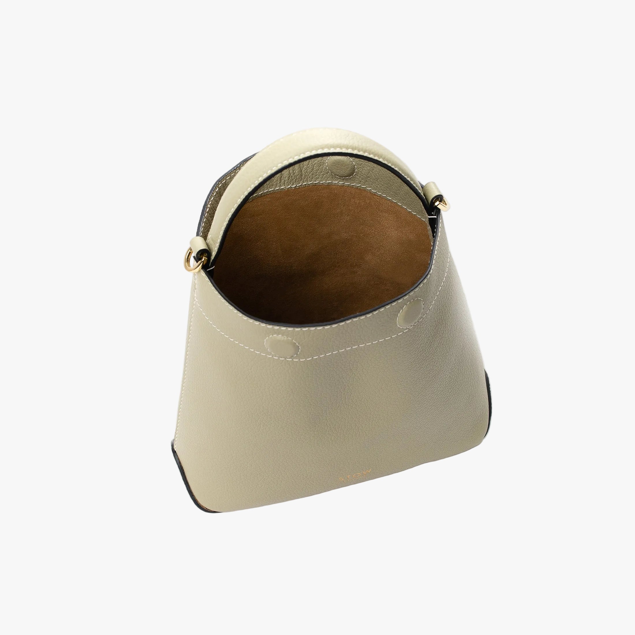 Top view of STOW London's Mini Curve in Pale Green pebbled leather with magnets open showing cognac suede interior lining on a light grey background