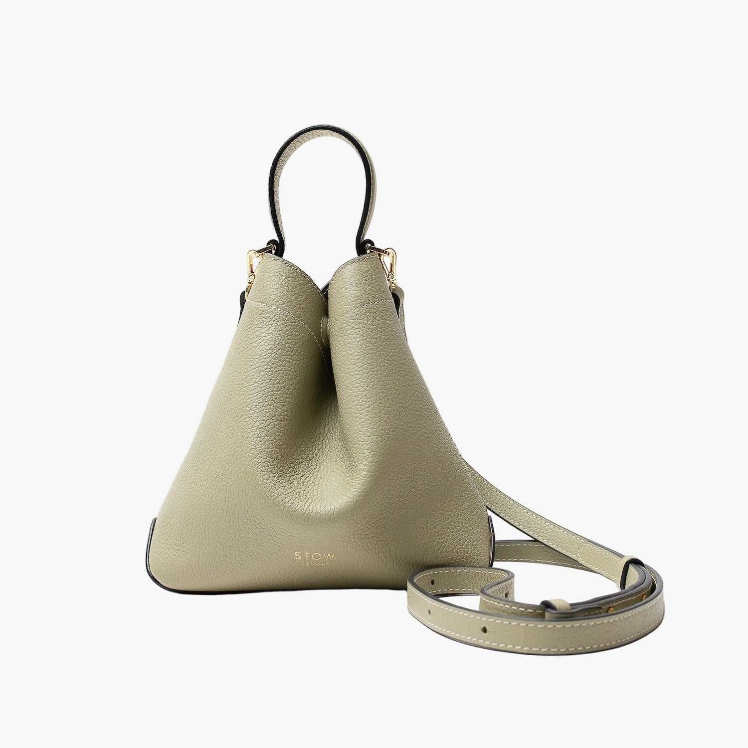 STOW London's Mini Curve in Pale Green pebbled leather and detachable leather crossbody strap on a light grey background