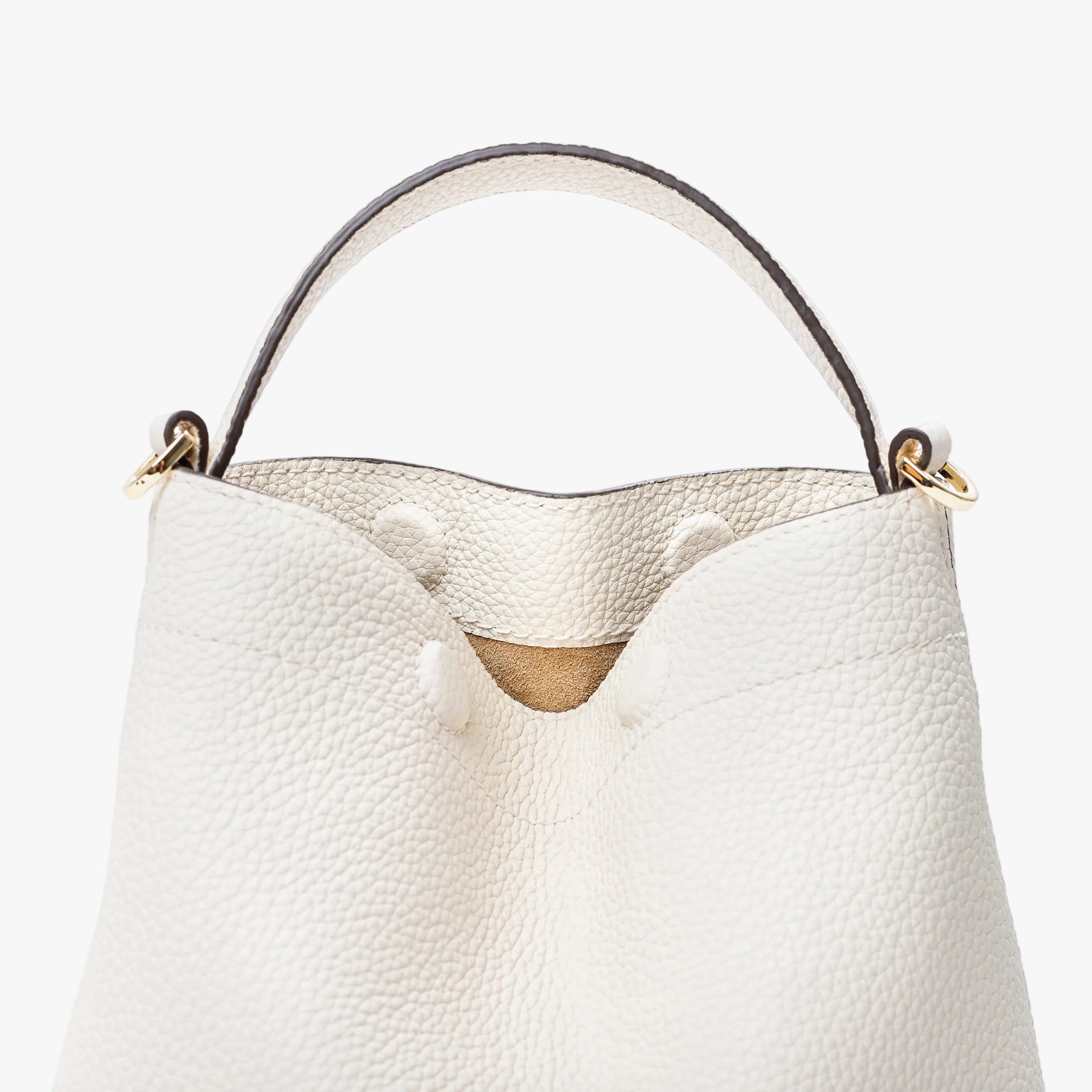 Close up of STOW London's Mini Curve in Spring Moon pebbled leather featuring hidden magnets, suede lining and gold hardware on a light grey background