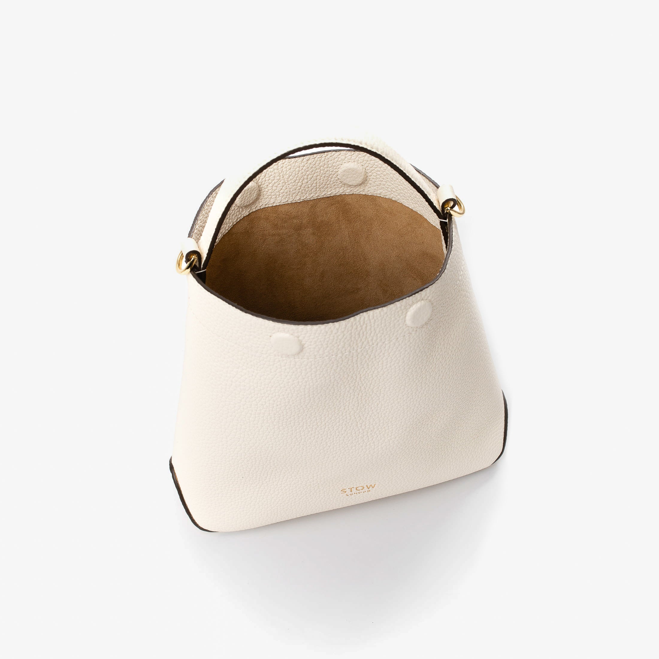 Top view of STOW London's Mini Curve in Spring Moon pebbled leather with magnets open showing cognac suede interior lining on a light grey background