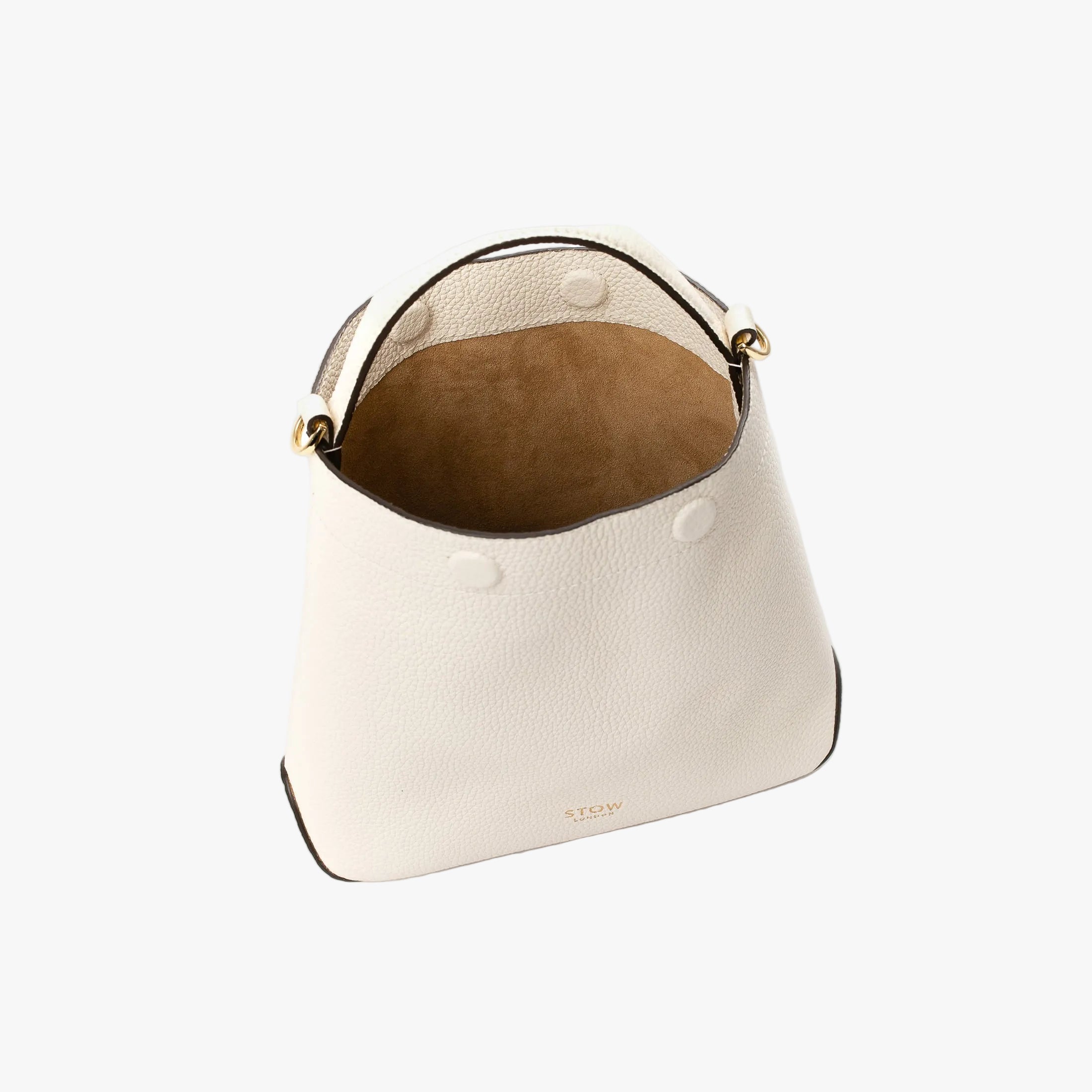 Top view of STOW London's Mini Curve in Spring Moon pebbled leather with magnets open showing cognac suede interior lining on a light grey background
