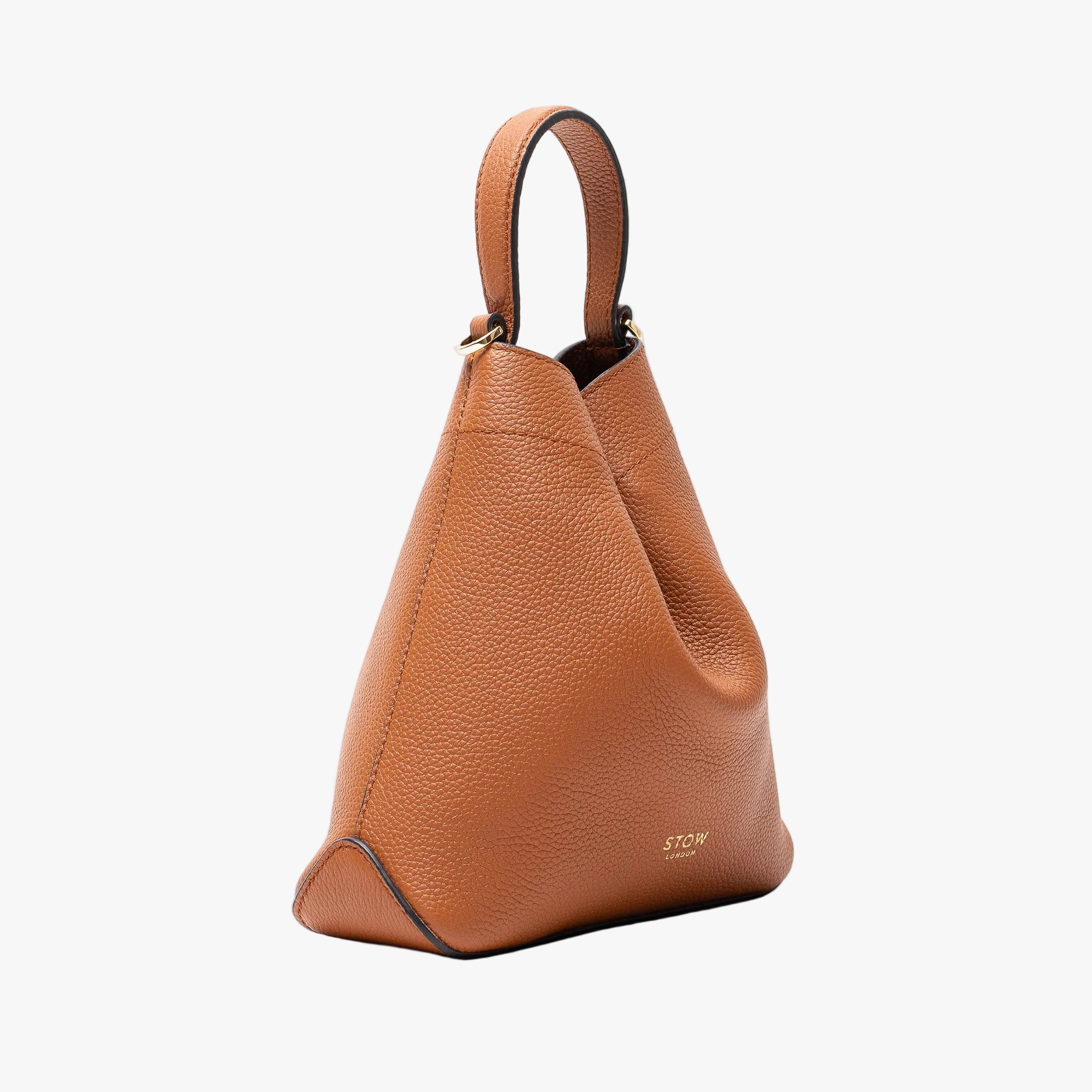 Off-axis view of Stow London's Mini Curve in Earth tan pebbled leather featuring gold details on a light grey background