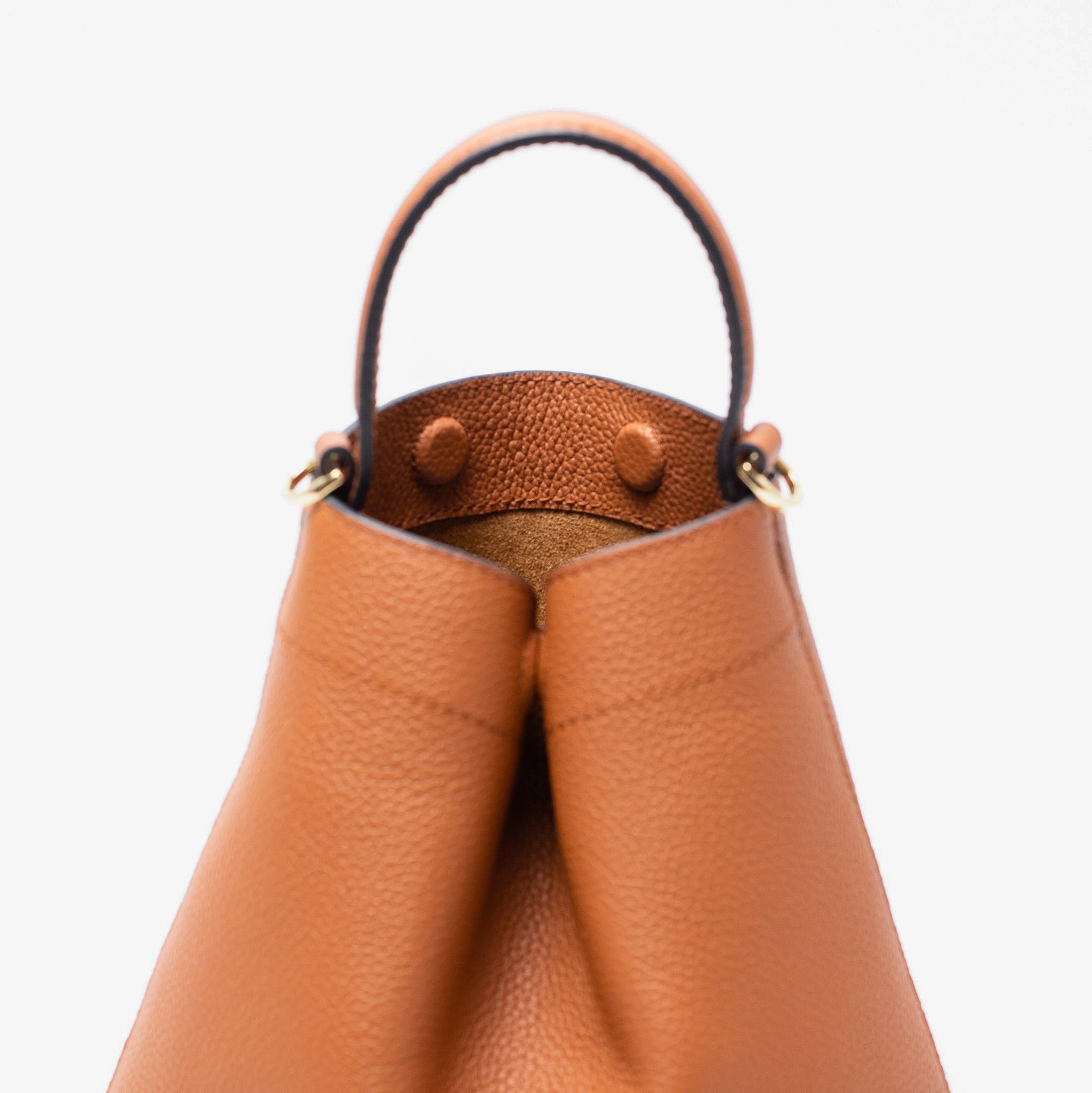 Close up of Stow London's Mini Curve in Earth tan pebbled leather featuring hidden magnets, suede lining and gold hardware on a light grey background