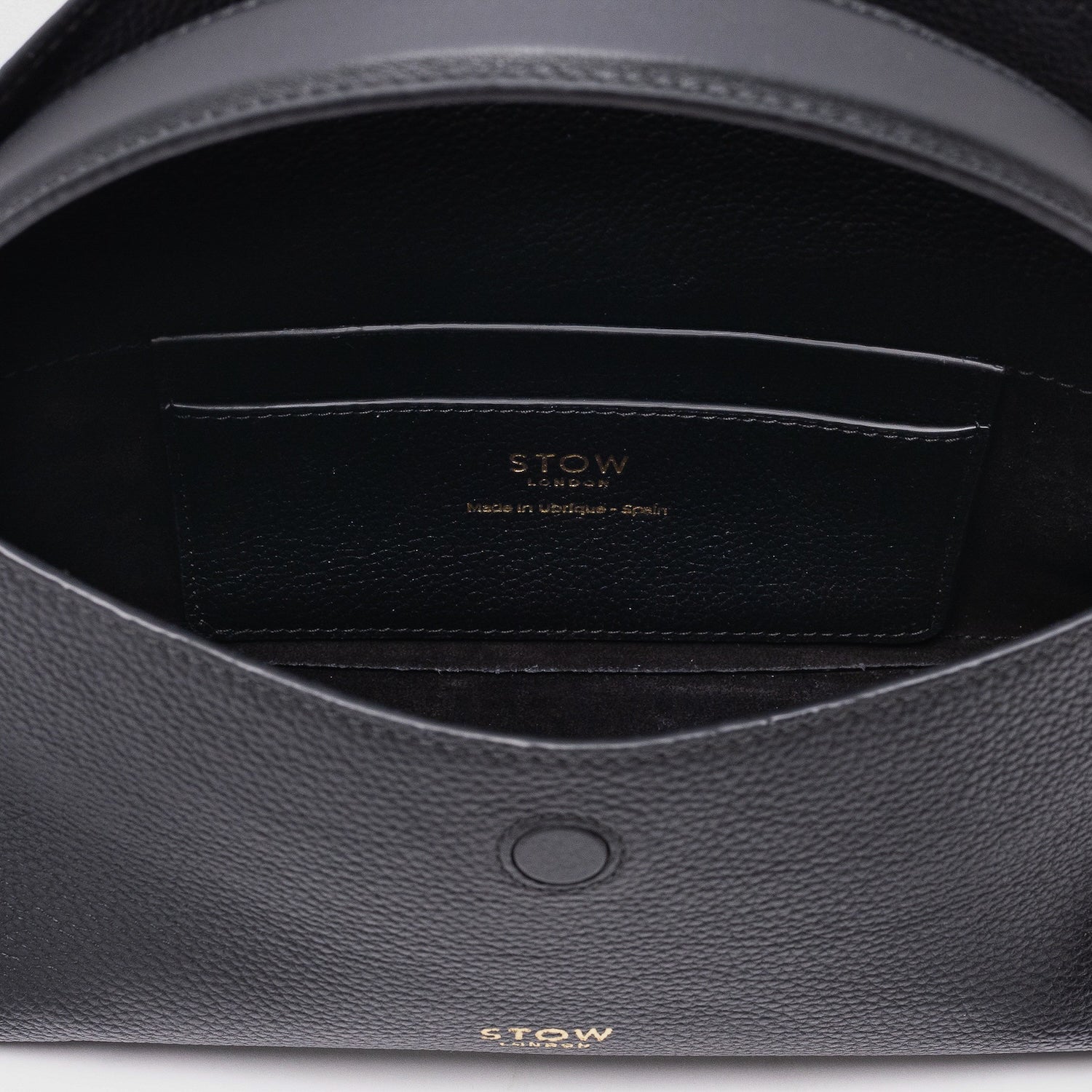 Close up of the interior of STOW London's Mini East West in Black pebbled leather featuring internal slip pocket on a light grey background