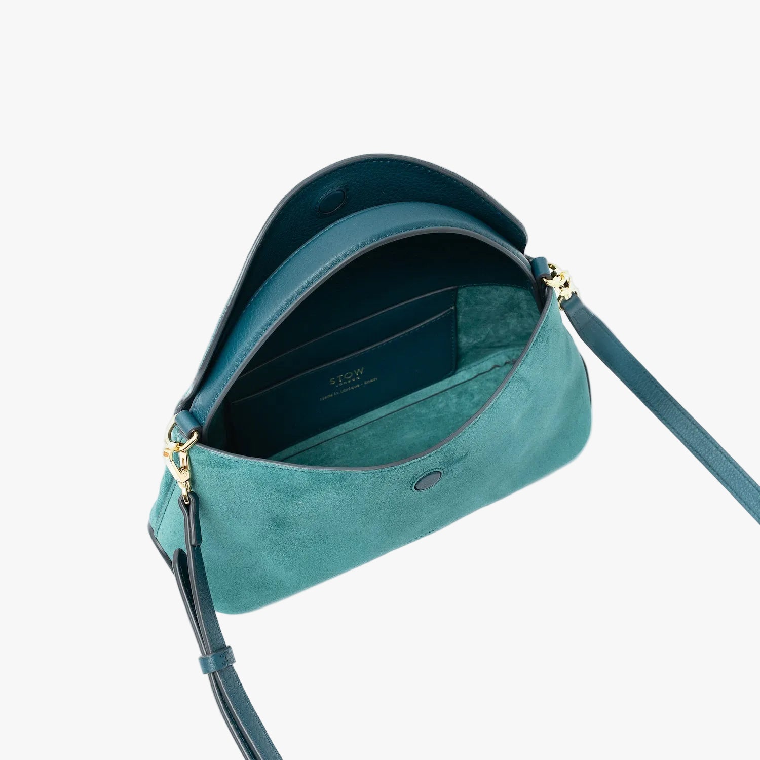 STOW London's Mini East West in Ocean Teal suede leather with flap open showing suede interior and slip pocket featuring gold-coated stainless steel hardware on a light grey background
