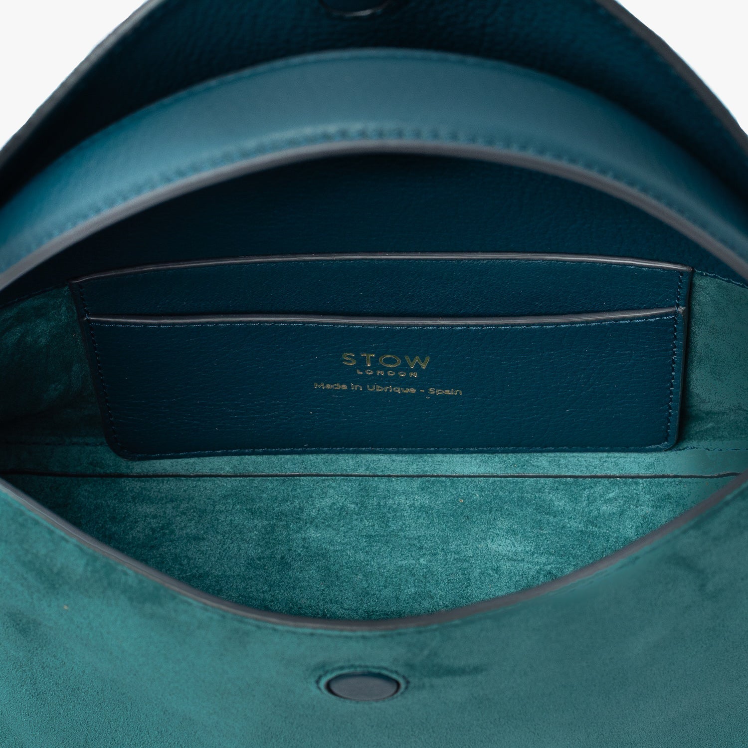 Close up of the interior of STOW London's Mini East West in Ocean Teal suede leather featuring internal slip pocket on a light grey background