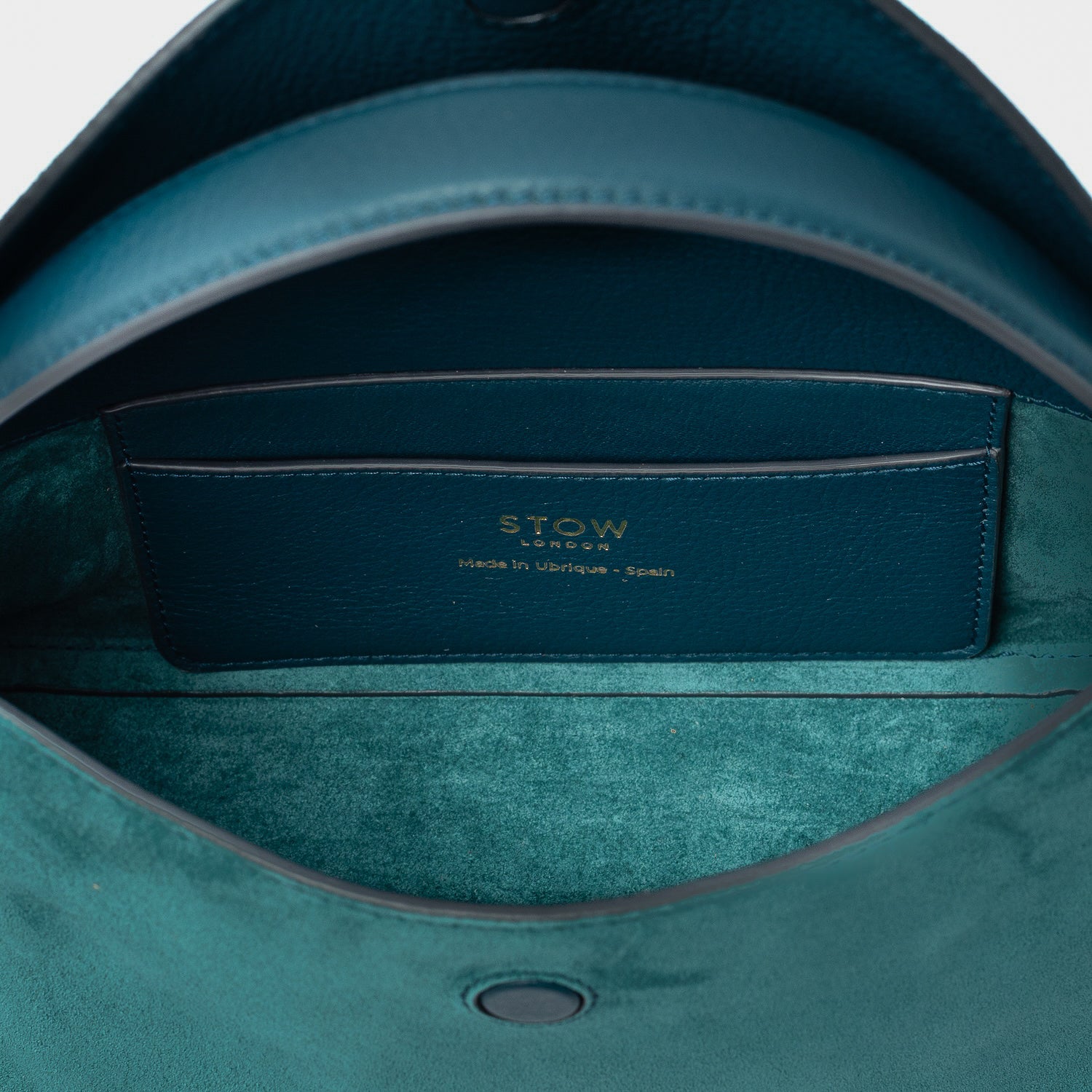 Close up of the interior of STOW London's Mini East West in Ocean Teal suede leather featuring internal slip pocket on a light grey background